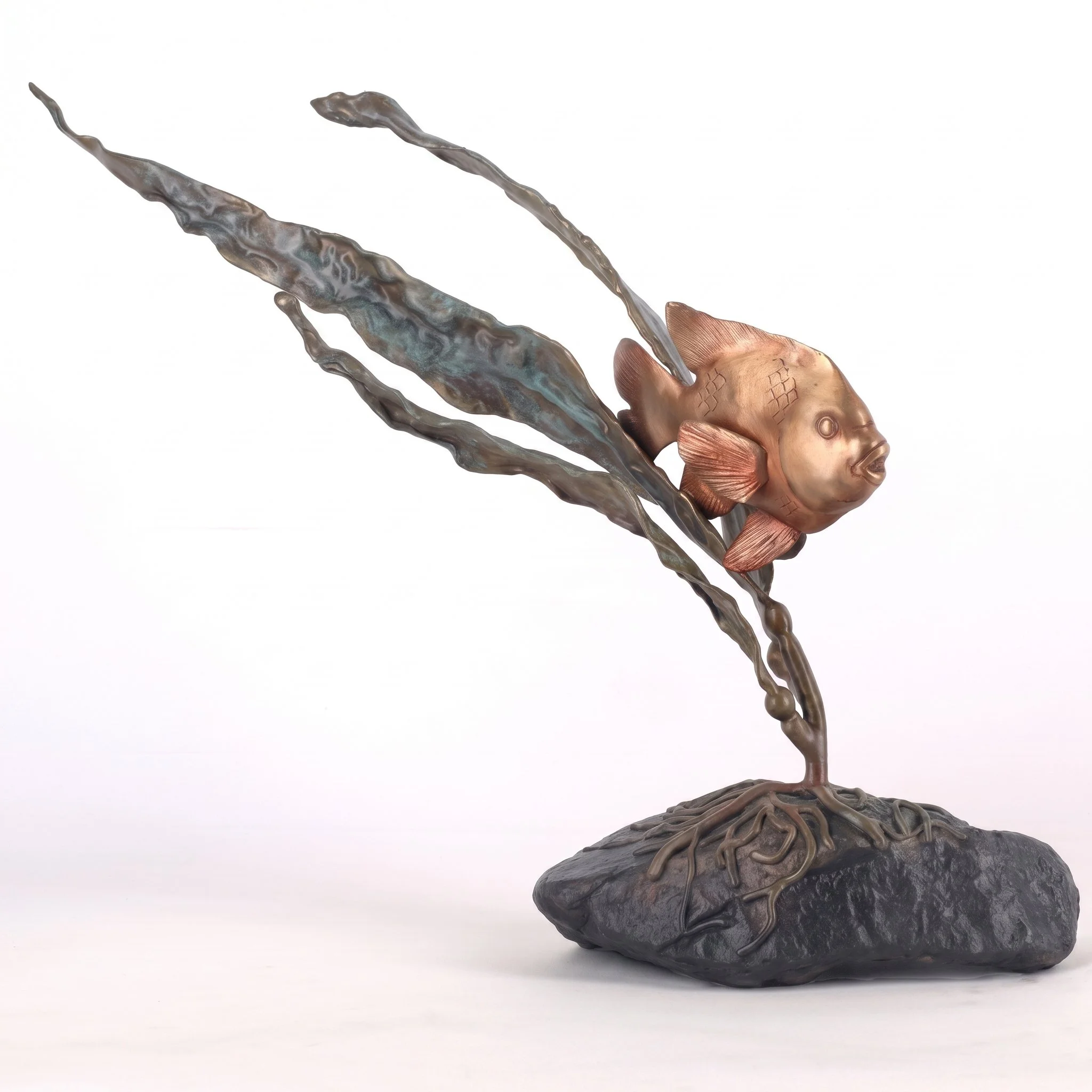 A metallic sculpture of a fish with elongated fins, sitting on a dark stone base.
