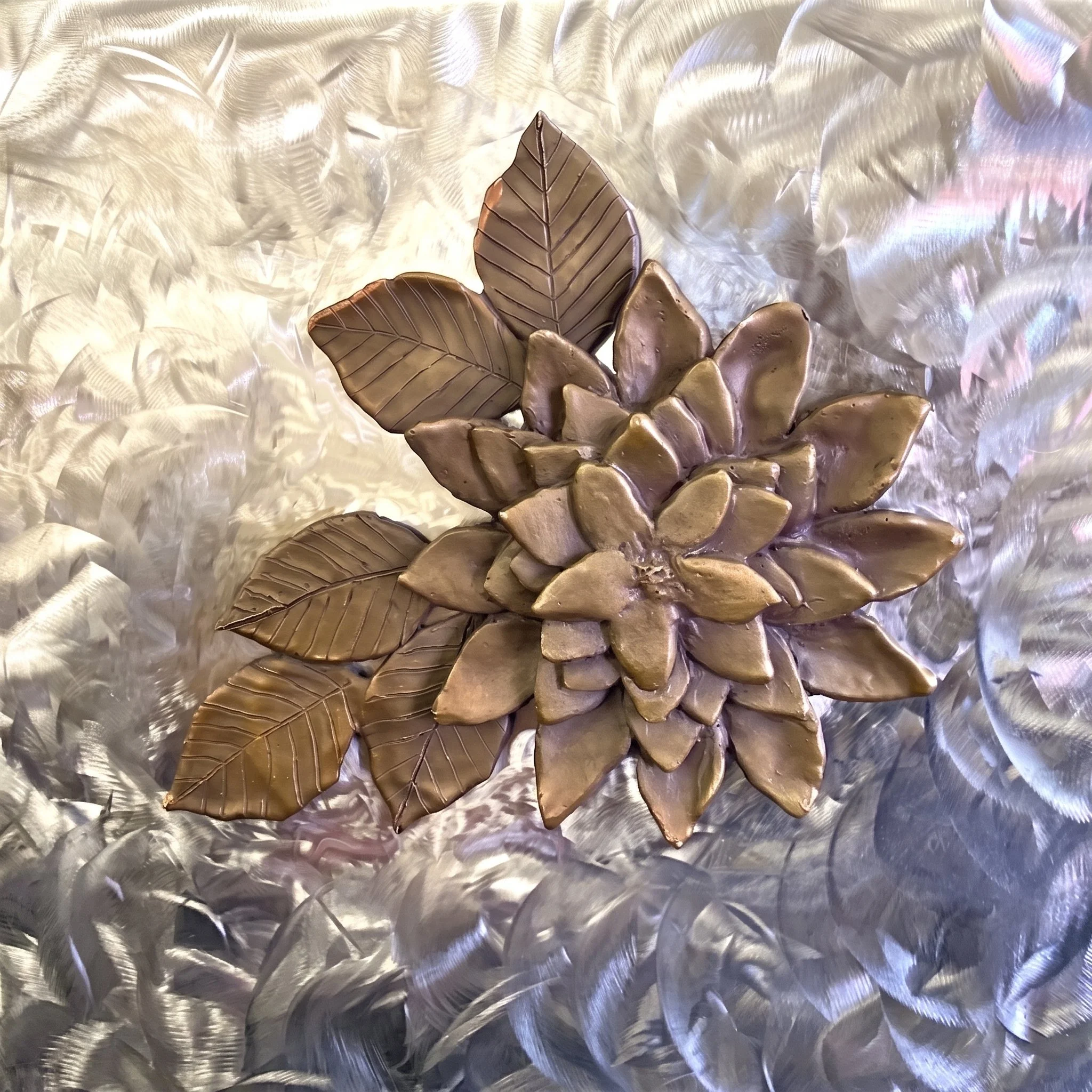 Chocolate leaves and flowers on a shiny, textured surface.