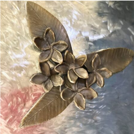 With guidance from sculptor and friend Manuelita Brown, I created seven bronze flowers, and she created the figure and the Kumeyaay Native American Hut in San Diego. "Plumeria" By Judy Salinsky