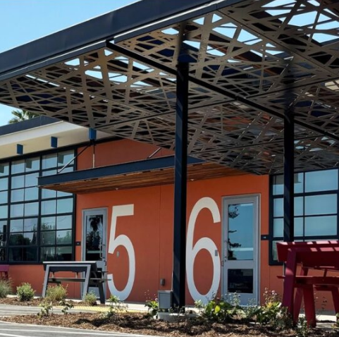 Modern building with large orange wall displaying the numbers 5 and 6, glass windows, and outdoor seating area