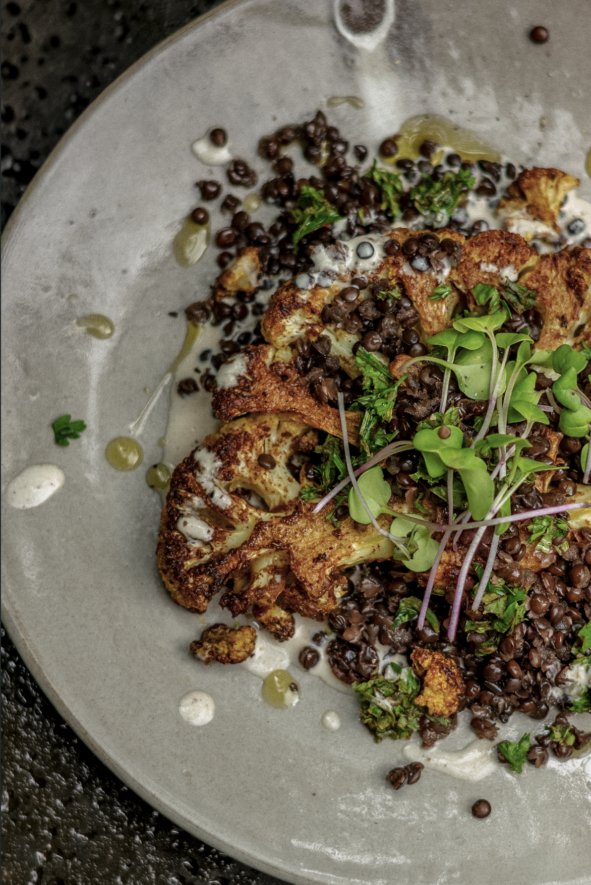 Roasted cauliflower with lentils and microgreens on a ceramic plate