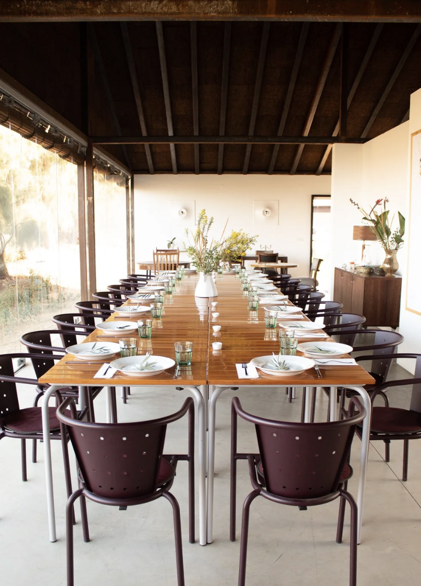 A long table set for a shared meal under a timber roof