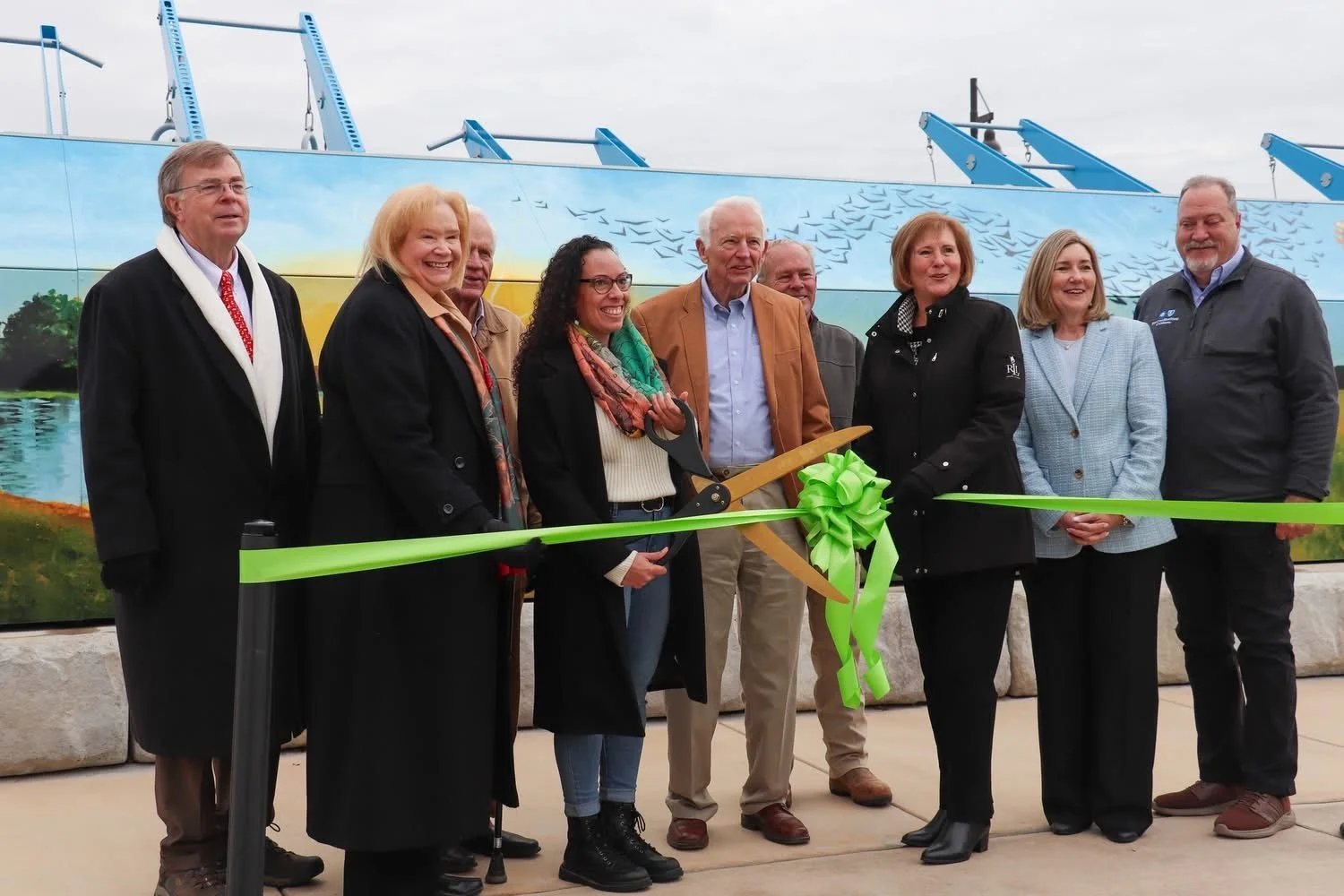 Corinna Nicole of Huntsville, AL, cuts the ribbon at the opening of the Hays Farm Park outdoor fitness court featuring her mural.