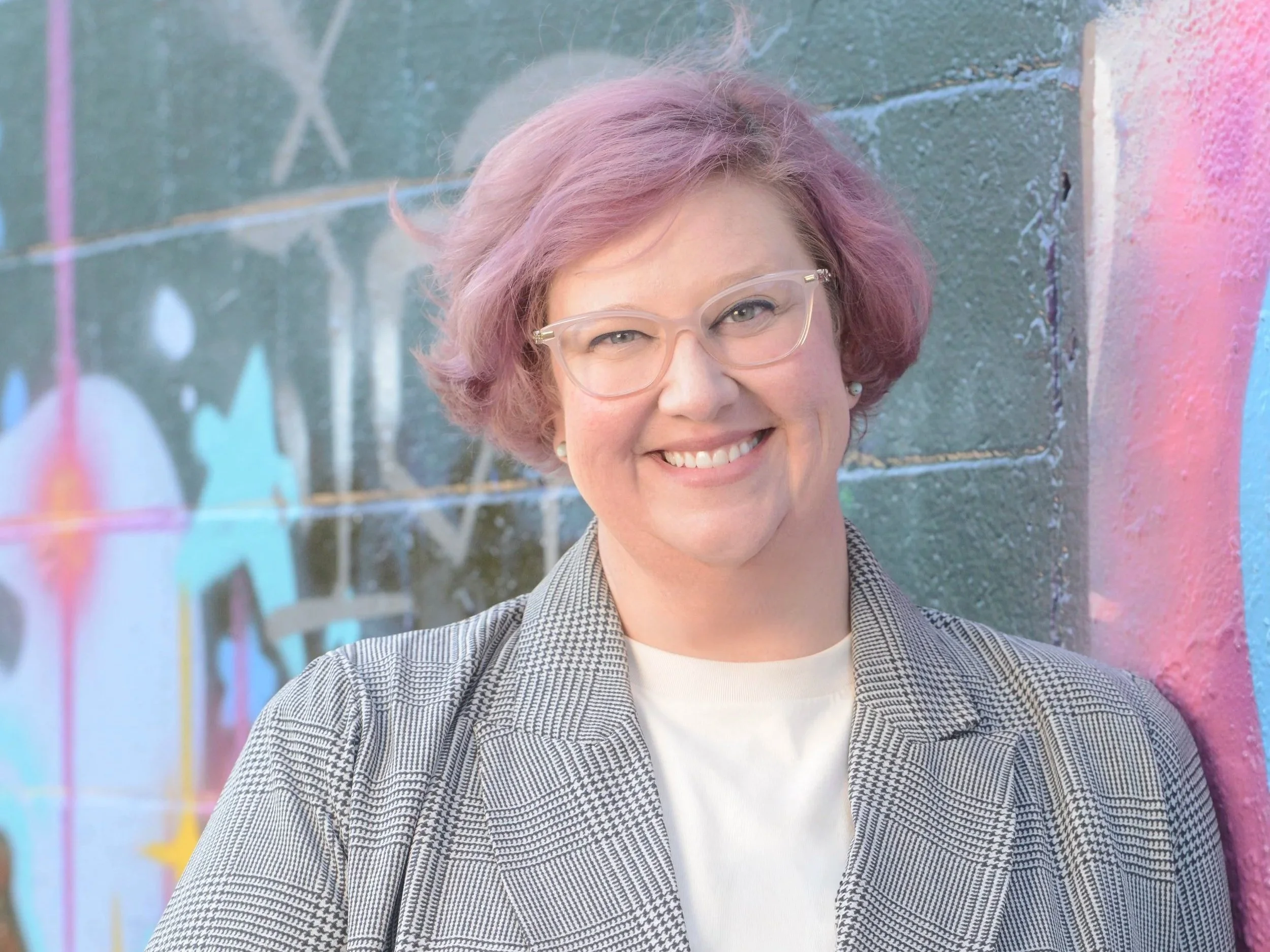 Mandy Parida, MA, LMHC standing against graffiti wall in West Seattle.