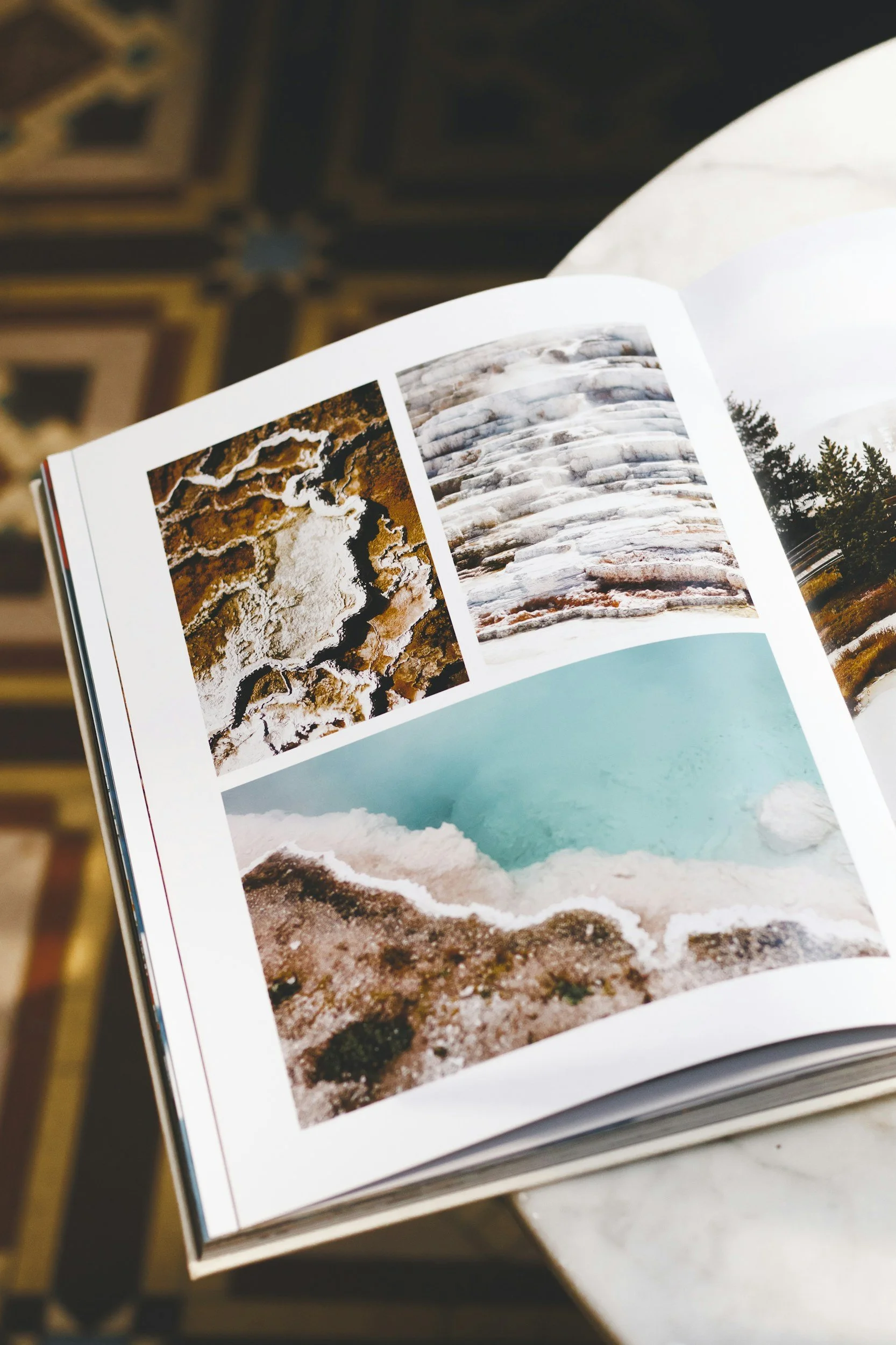 Open book showing photographs of natural landscapes, including salt formations and a body of water, on a table.