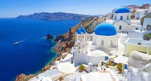 White buildings with blue domes overlooking the deep blue sea at Santorini, Greece.