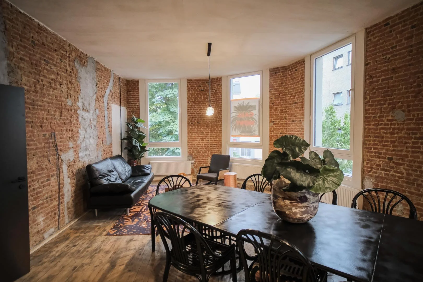 Communal living room in student accommodation with brick walls, large windows, seating and a dining area