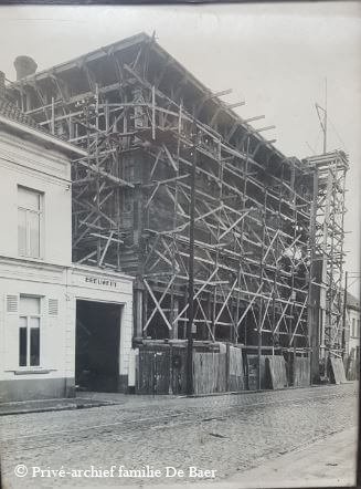 A building under construction with extensive wooden scaffolding surrounding it, next to an older building.