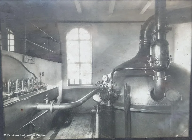 Black and white photo of an old industrial boiler room with piping, gauges, and a large window.