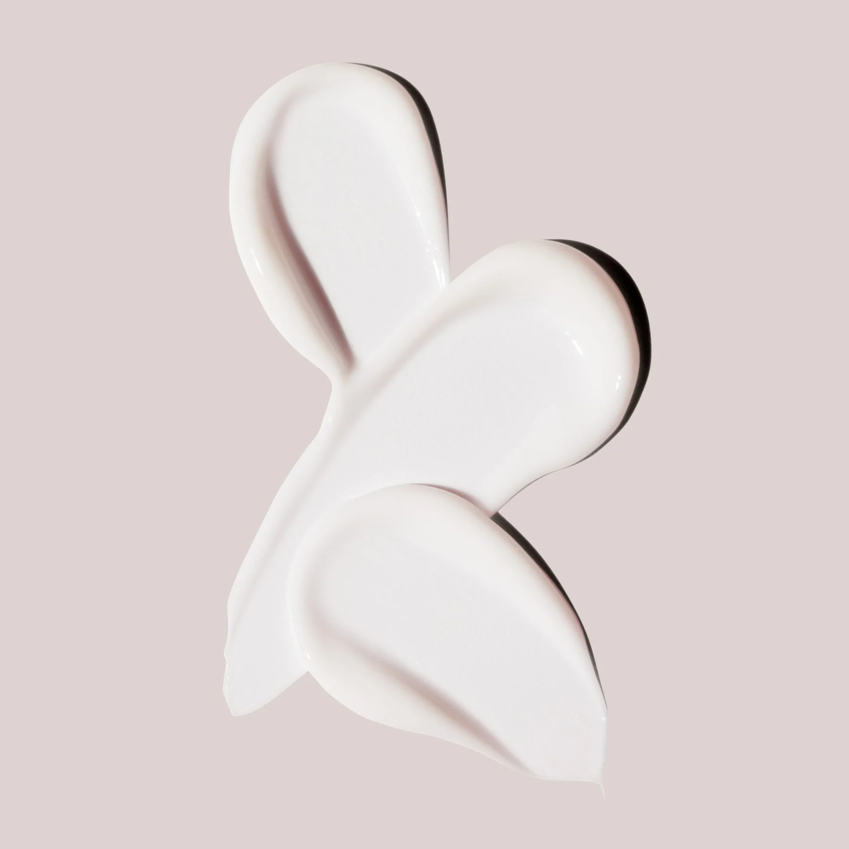 Close-up of a white abstract sculpture with smooth, curved surfaces against a light beige background.
