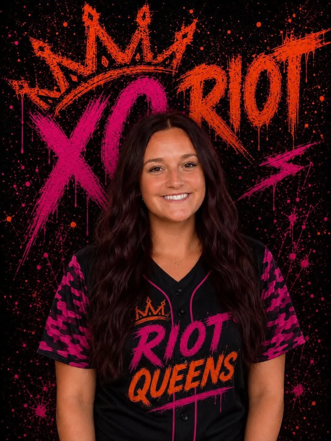 A woman with long dark wavy hair smiling in front of a black background with pink and orange graffiti-style text and designs. The text reads 'Riot Queens' and the woman is wearing a black and pink sports jersey with the same text.