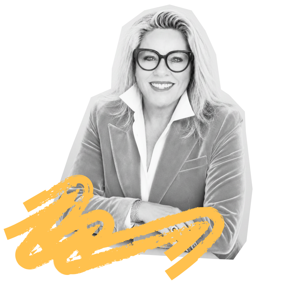 Kylie Ward smiling with glasses, wearing a blazer and collared shirt, sitting at a table with folded arms in a professional setting.