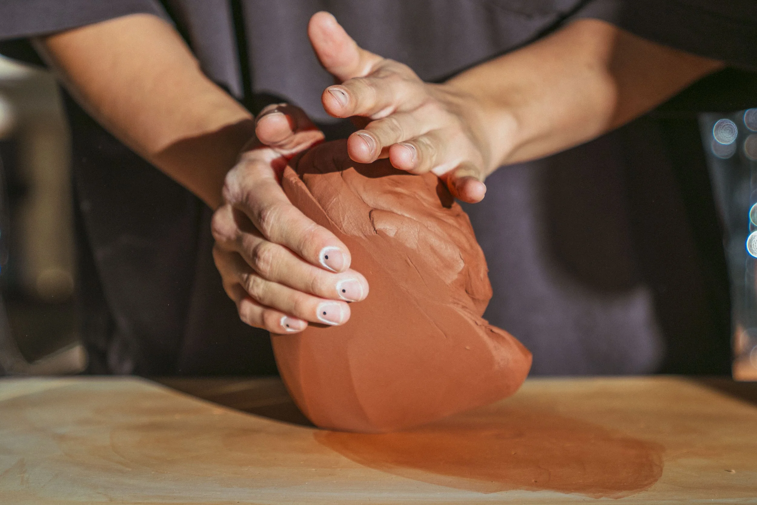 Person shaping a clay sculpture with their hands.