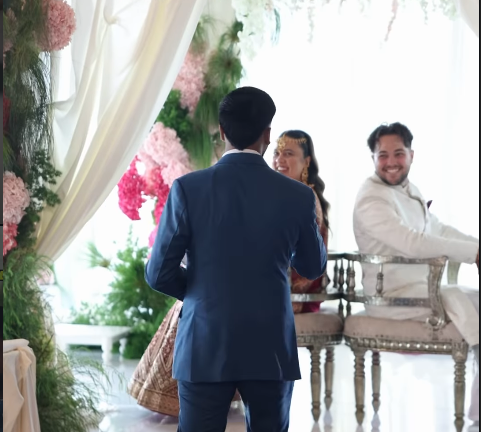 People at a wedding ceremony with floral decorations and a bright, airy background.