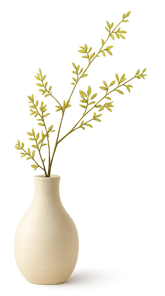 A white ceramic vase holding a branch of green leaves.