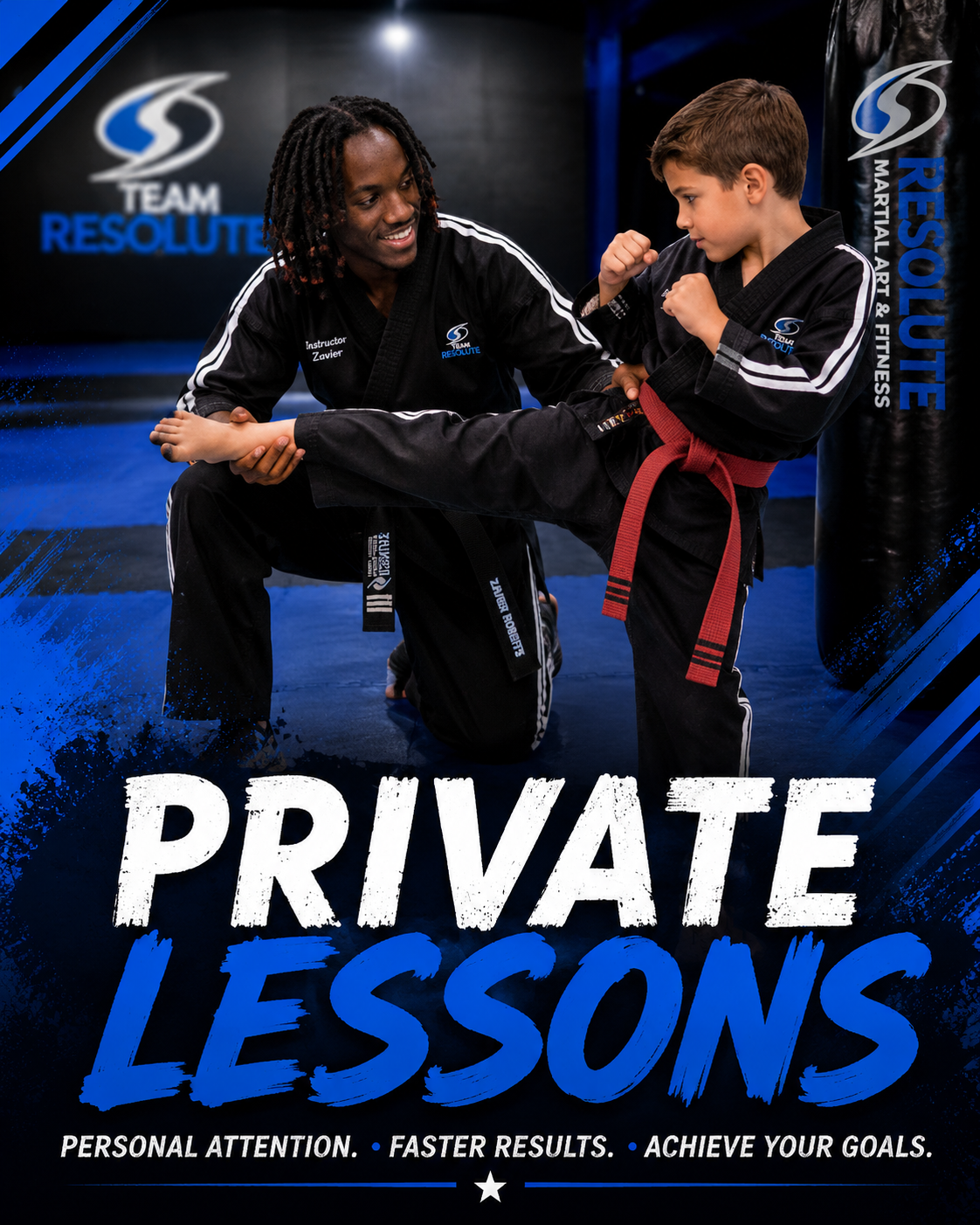 A martial arts instructor teaches a young boy how to perform a martial arts move, both wearing black gi uniforms with the instructor kneeling and holding the boy's leg during a private lesson at a martial arts gym.