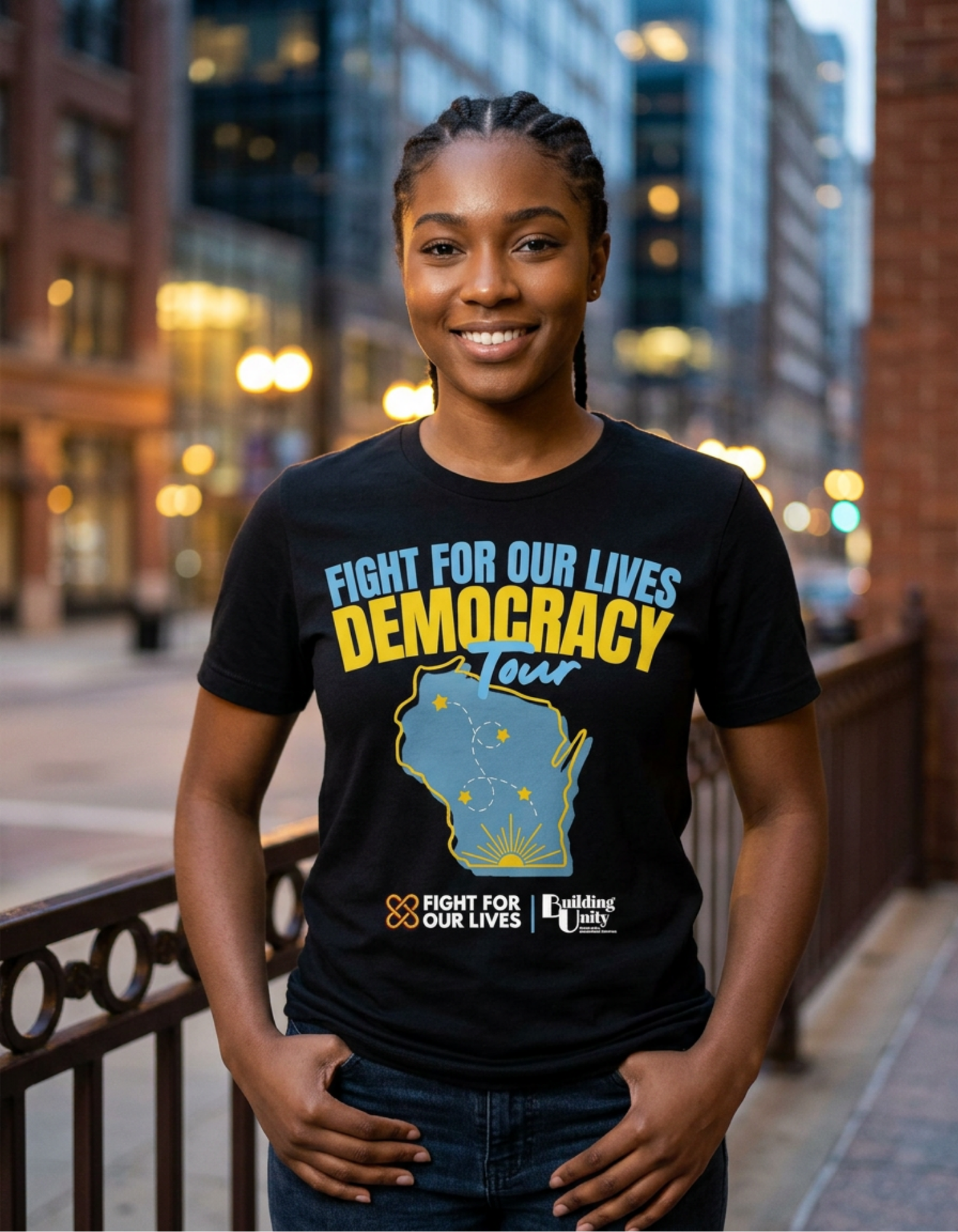 A woman smiling outdoors at dusk, wearing a black T-shirt with a political message and graphic of Illinois and a sunrise.