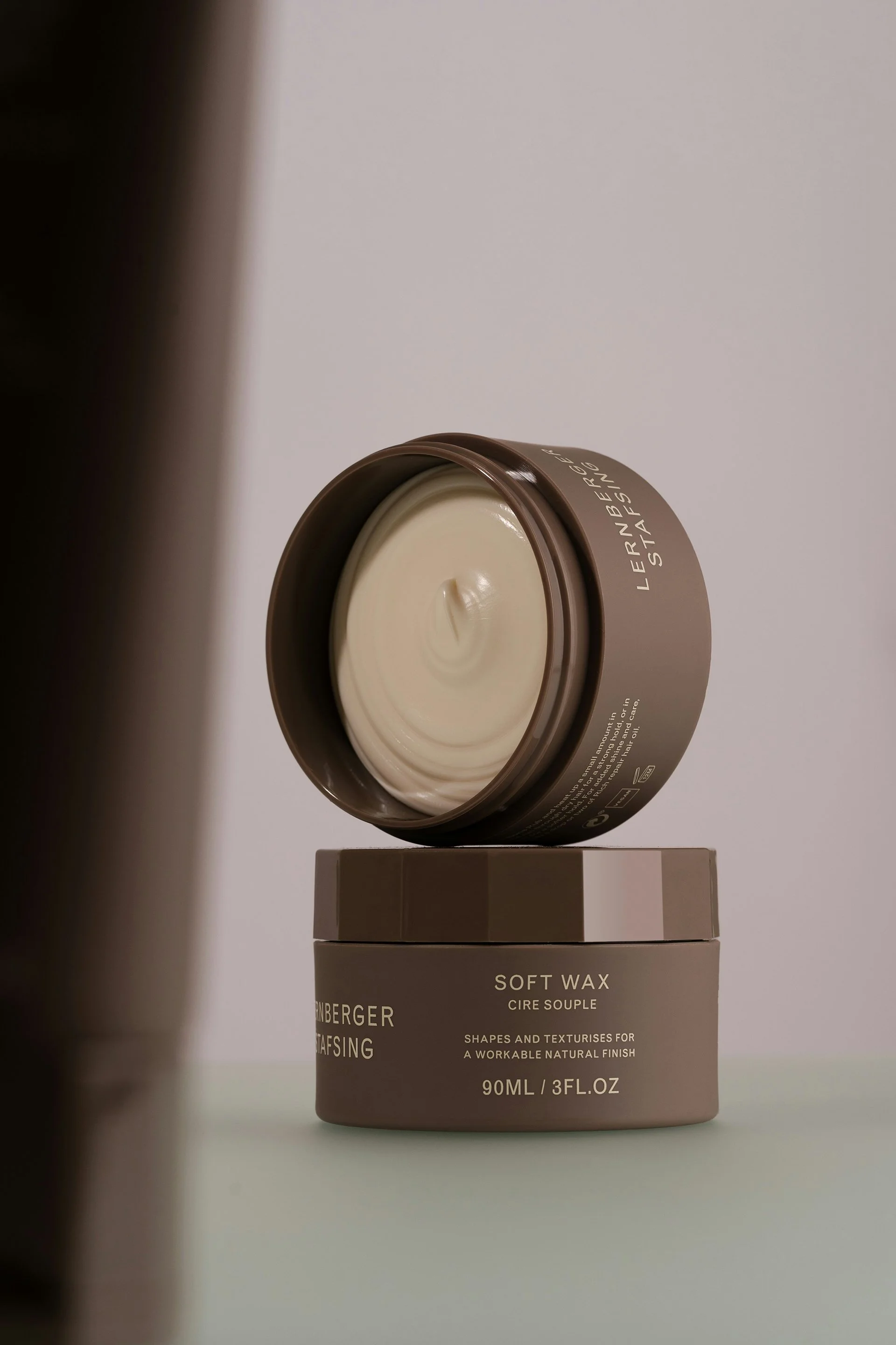 A small brown container of soft wax with white wax inside, placed on top of a beige box that reads 'SOFT WAX'.