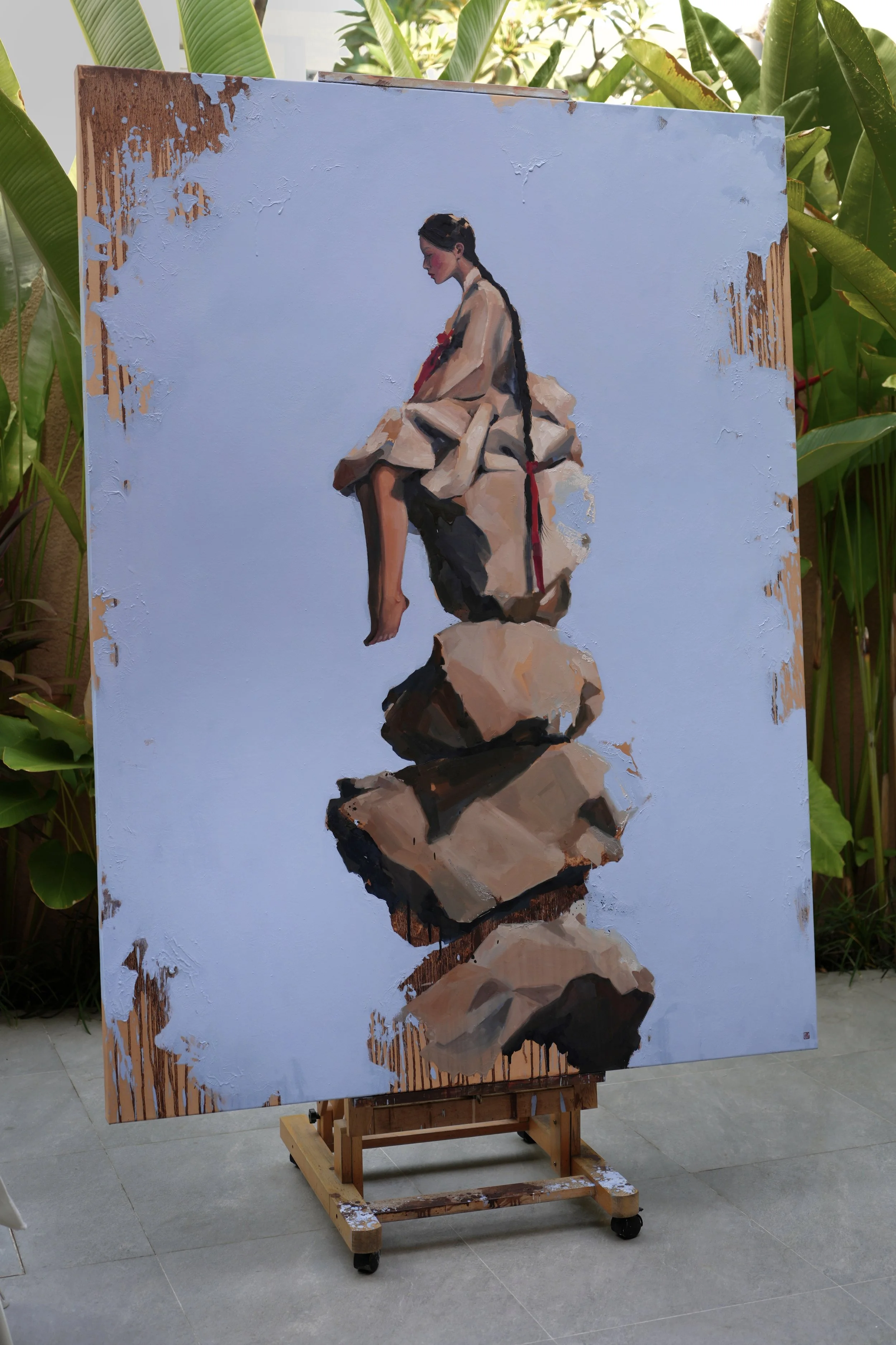 Cairn by Marina Ogai – the large canvas photographed outdoors with tropical plants behind it