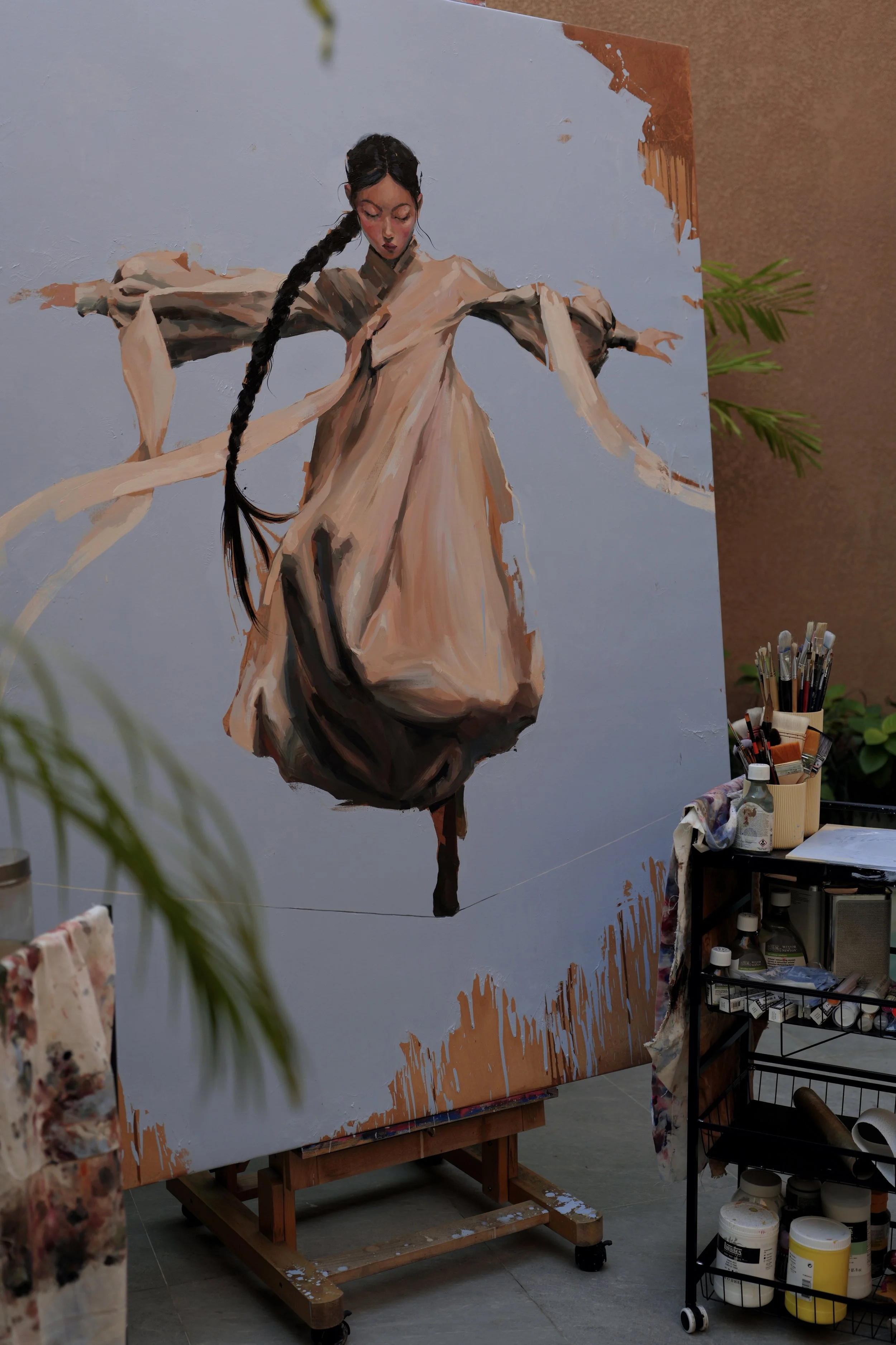 Large oil painting of a girl in hanbok balancing on a line, seen in the studio behind brushes and plants, from Given by Marina Ogai