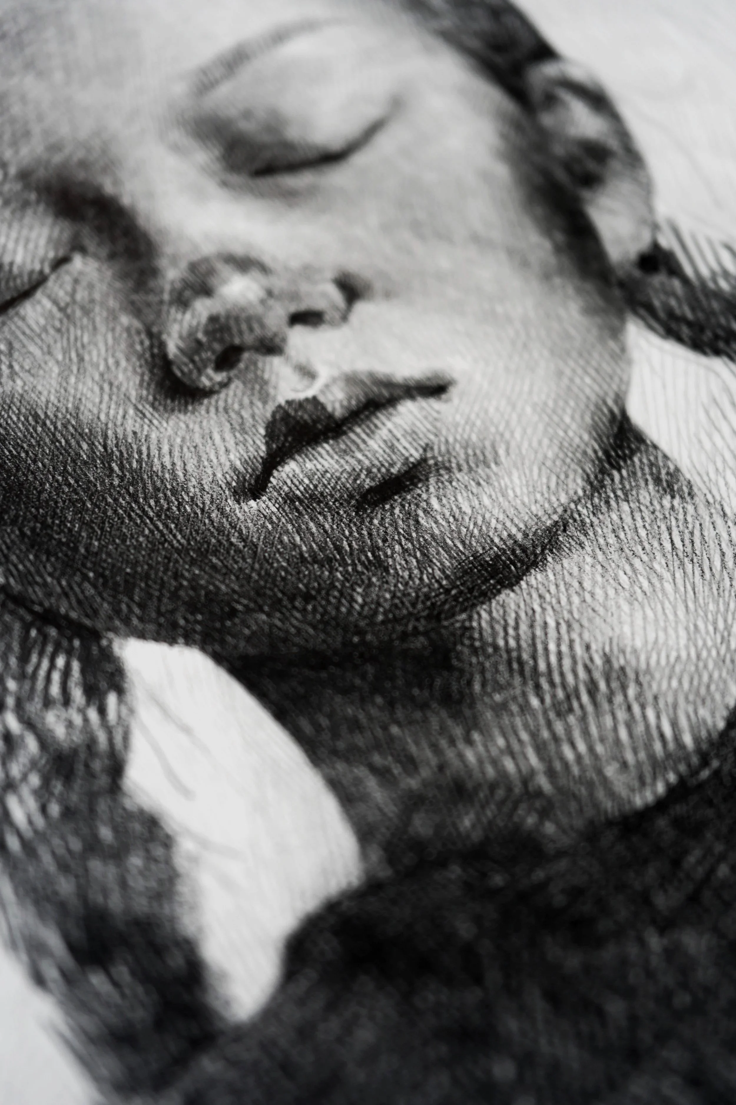 Close-up of a pencil drawing from The In-Between series by Marina Ogai: a face with closed eyes in dense hatching.