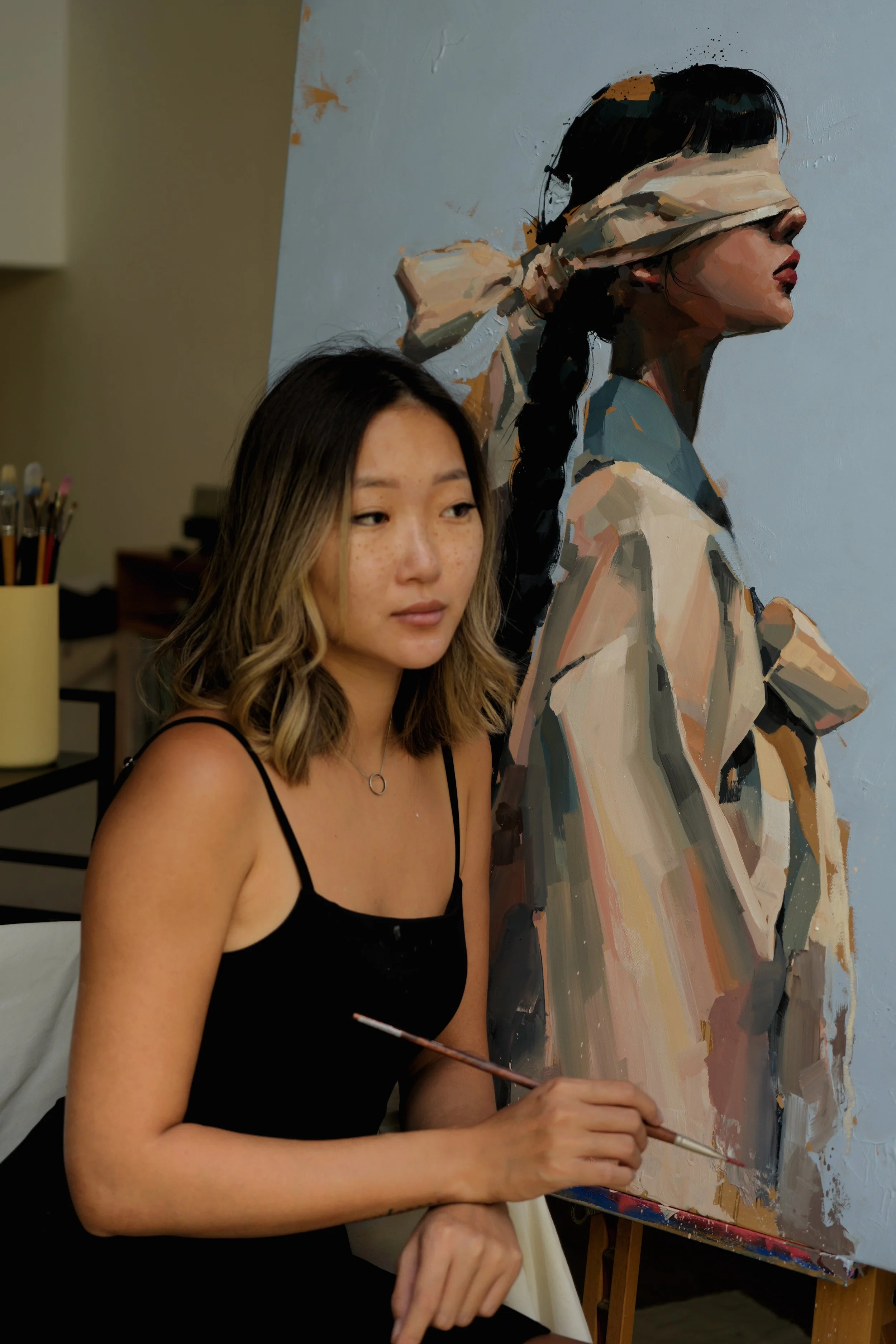 Marina Ogai with brush in hand beside the finished canvas in her studio, oil on linen, from Given