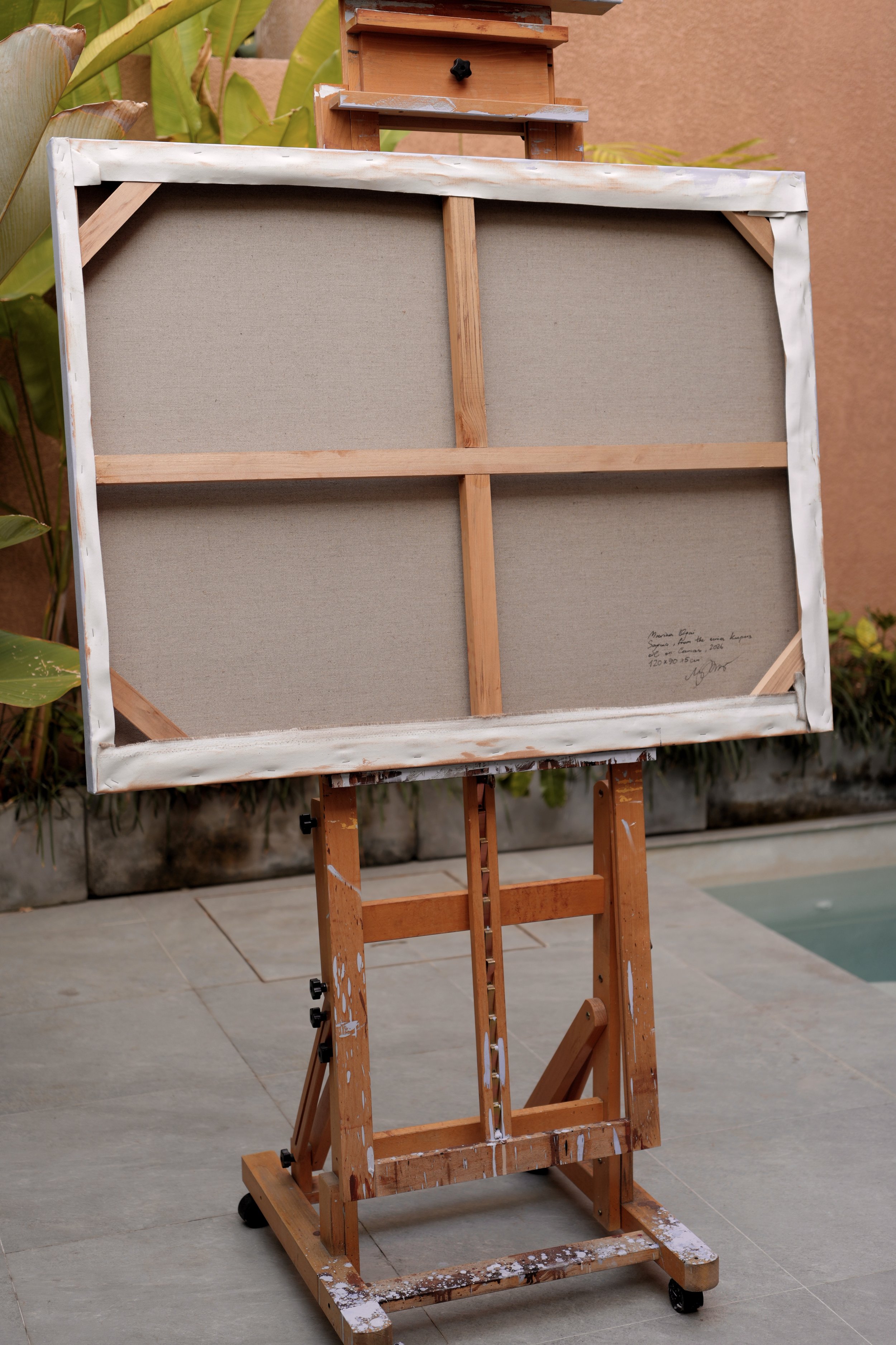 Back of the stretched linen canvas on a wooden easel, stretcher bars and signature visible, Sagwa by Marina Ogai