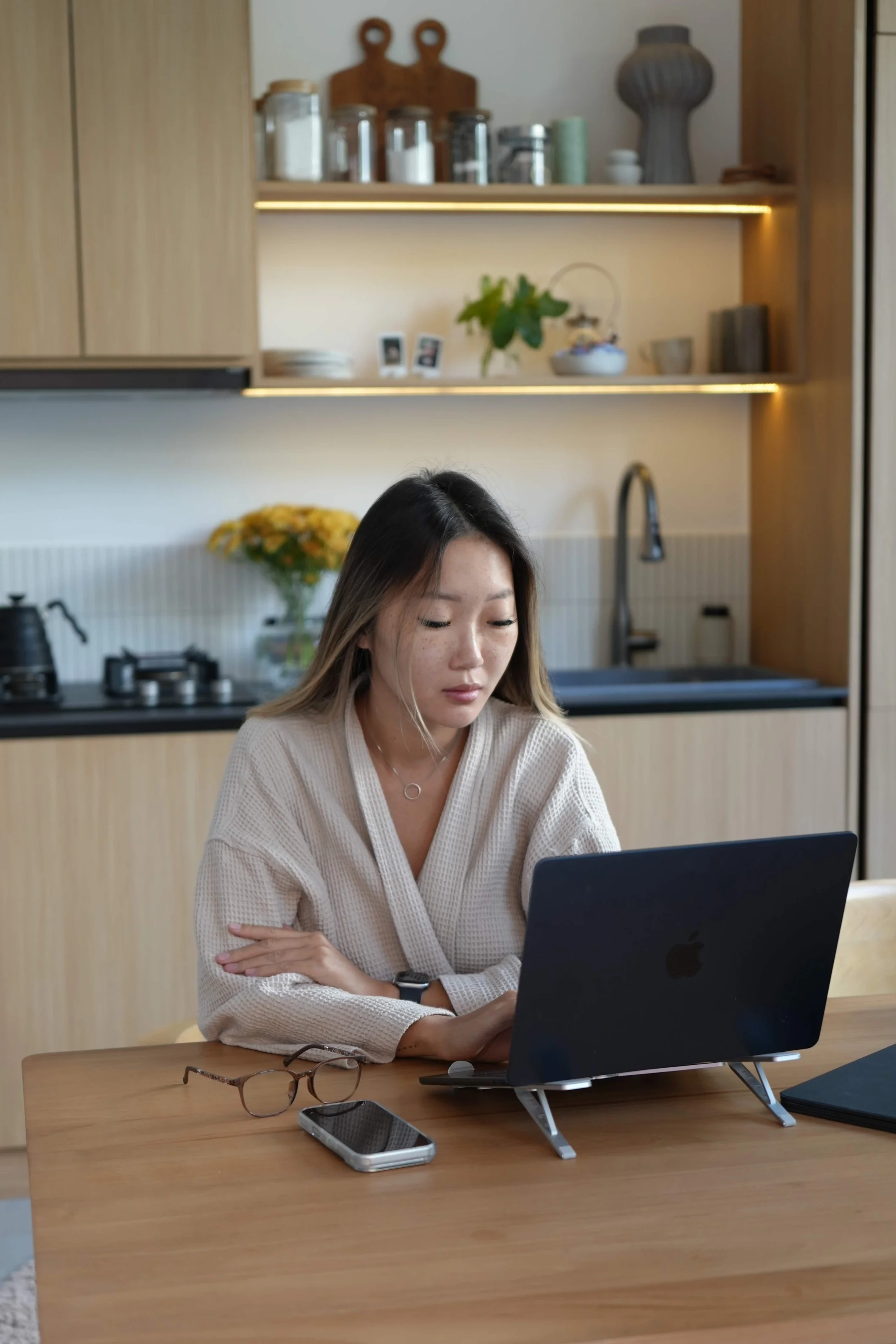 Marina Ogai in a robe at her kitchen table early in the morning, writing on a laptop.