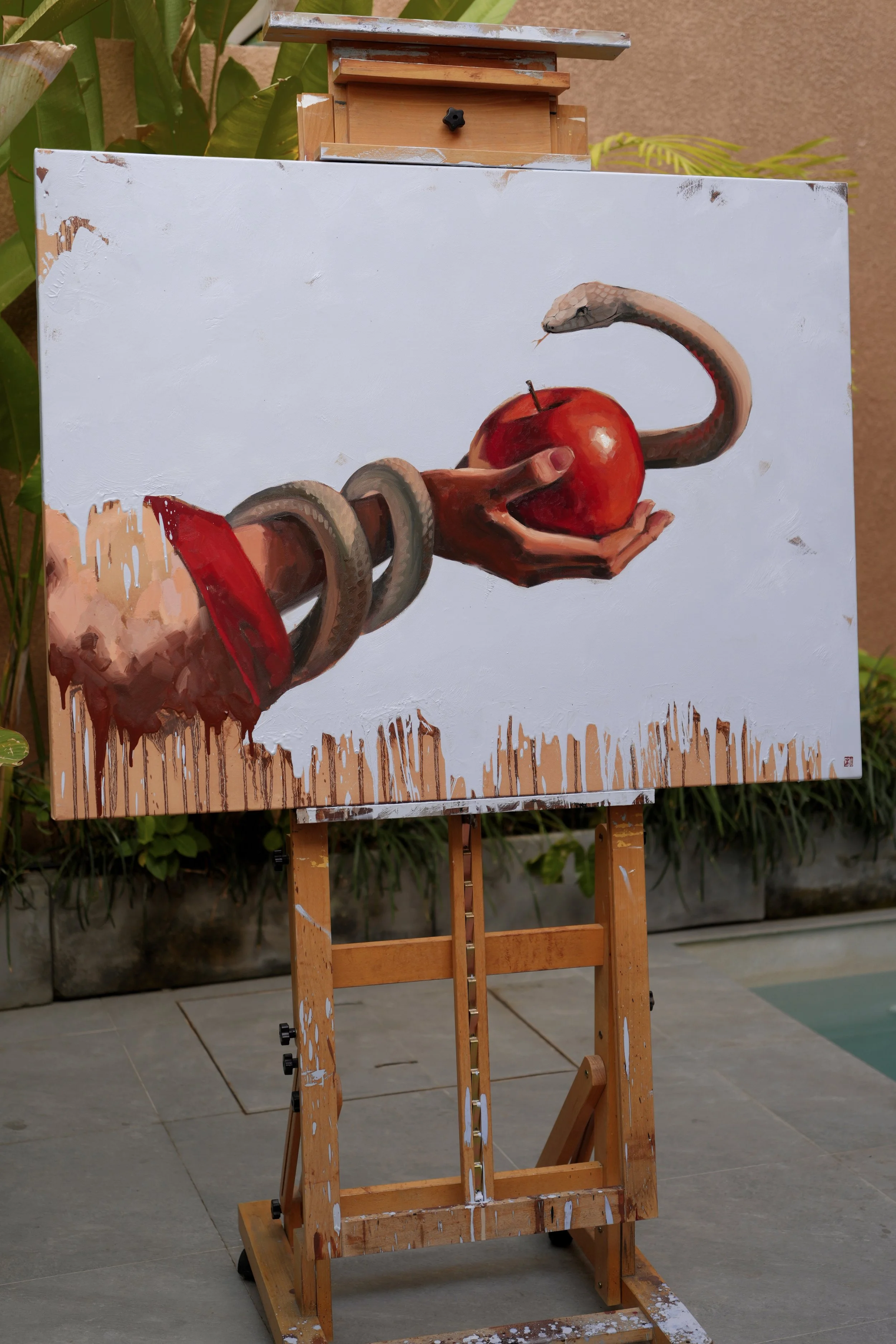 Sagwa by Marina Ogai on a wooden easel outdoors, a hand offering an apple to a snake, oil on linen canvas