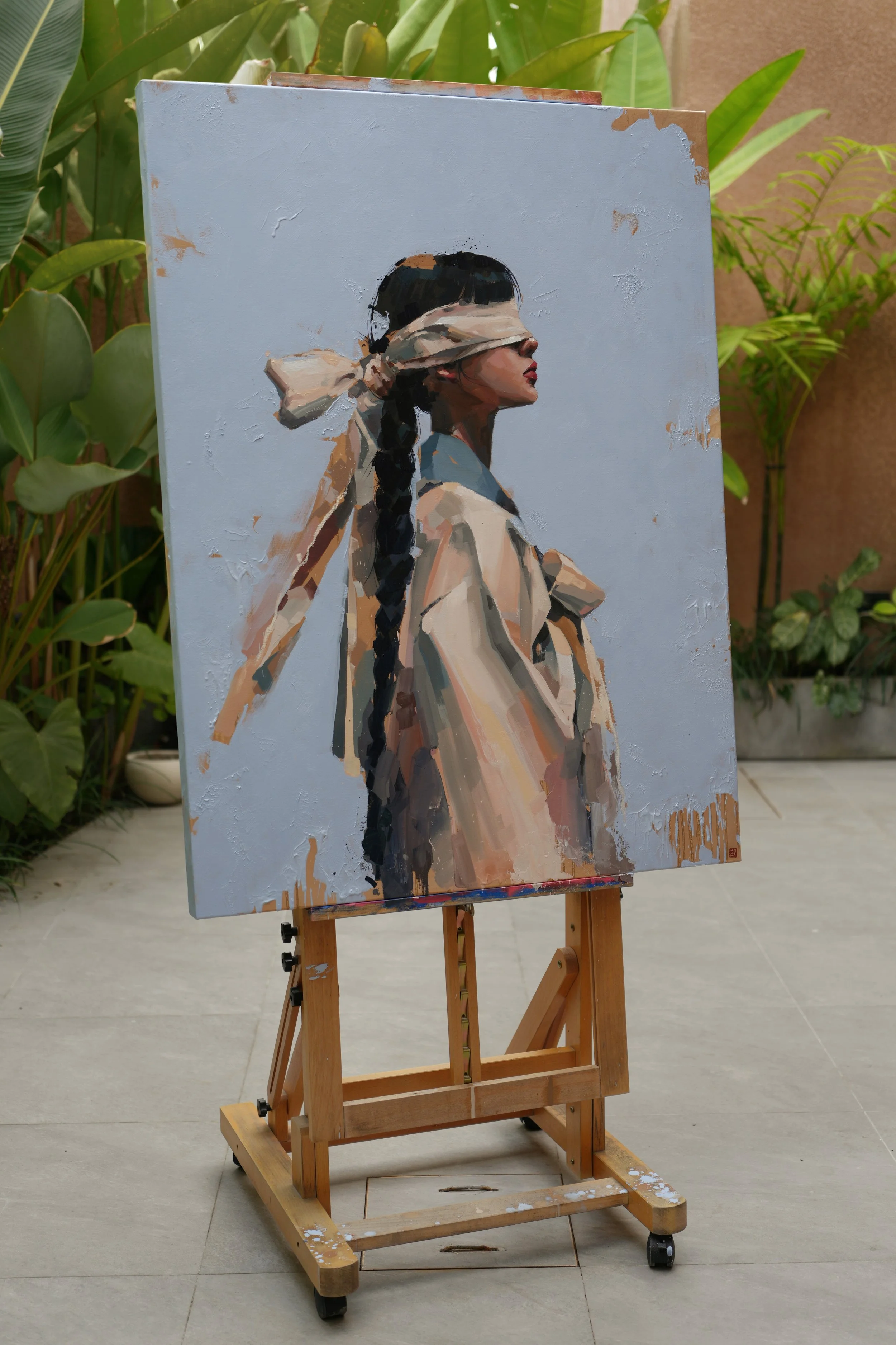The finished canvas on a wooden easel outdoors among tropical plants at the artist's Bali studio, oil on linen, from Given