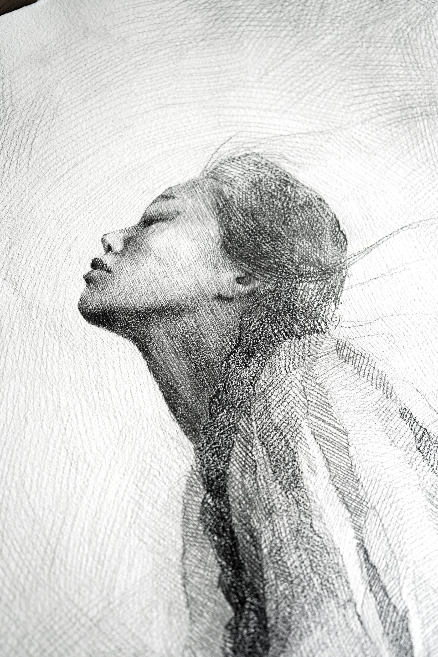 Detail of Fullness by Marina Ogai: the woman's face lifted to the sky, hair blown back, pencil hatching on paper