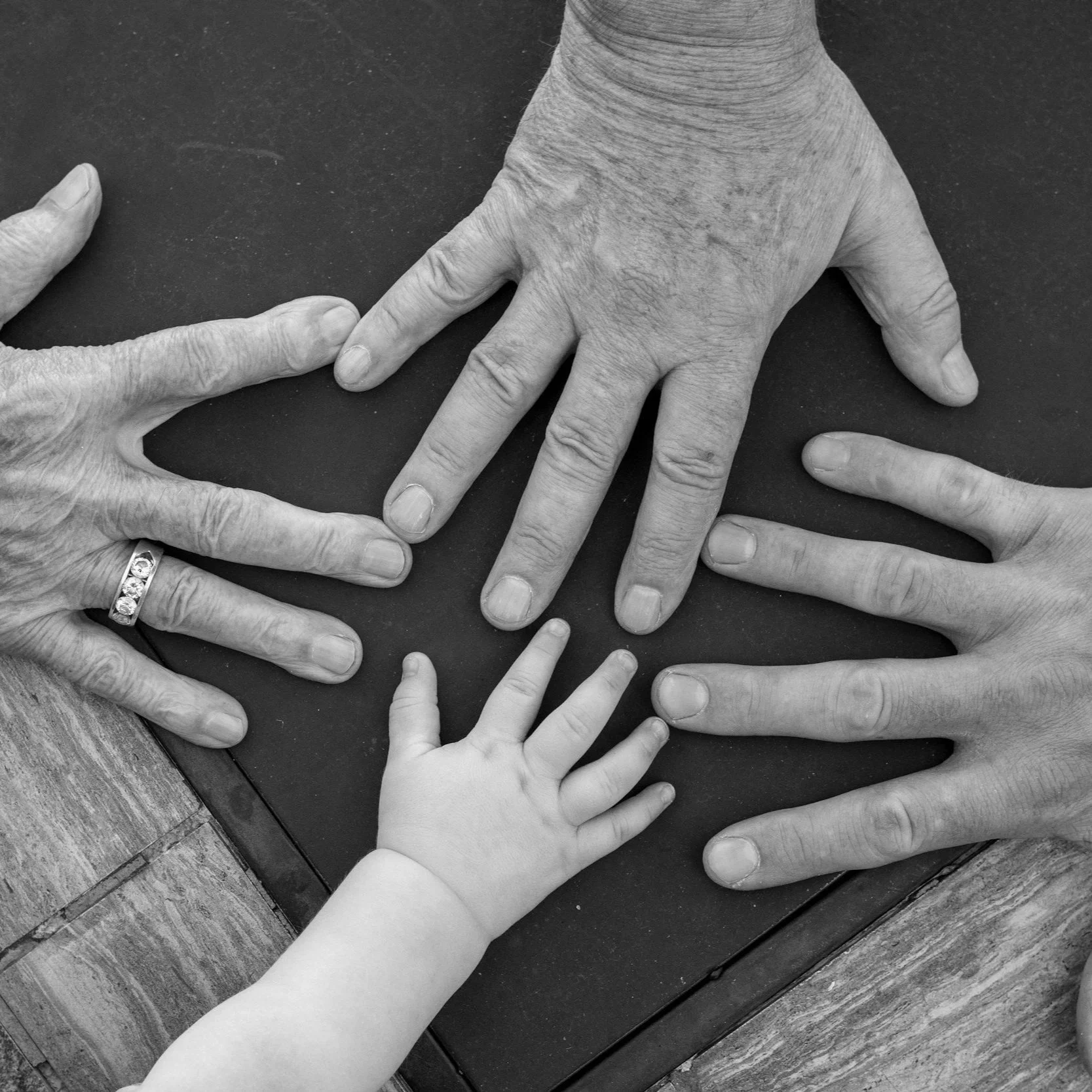Several hands from different age people laid on the same table