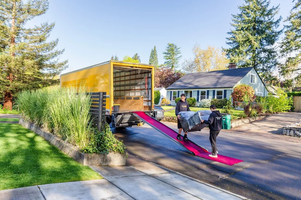 Movers wheeling furniture up a long ramp into the truck on a quiet street, office relocation in Beaverton