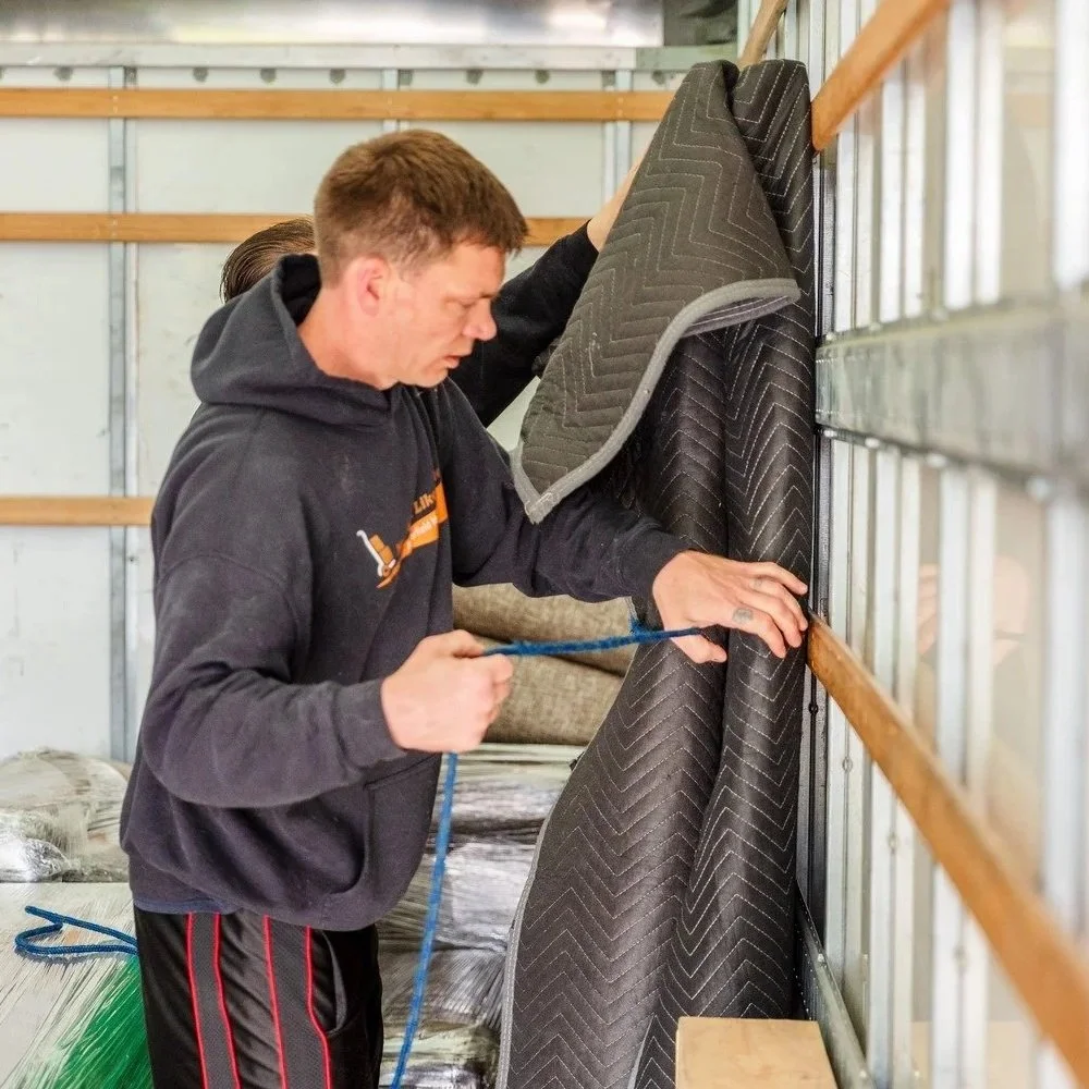 Professional Portland-area mover wraps furniture padding inside moving truck during westside residential relocation, protecting household items from damage and weather.