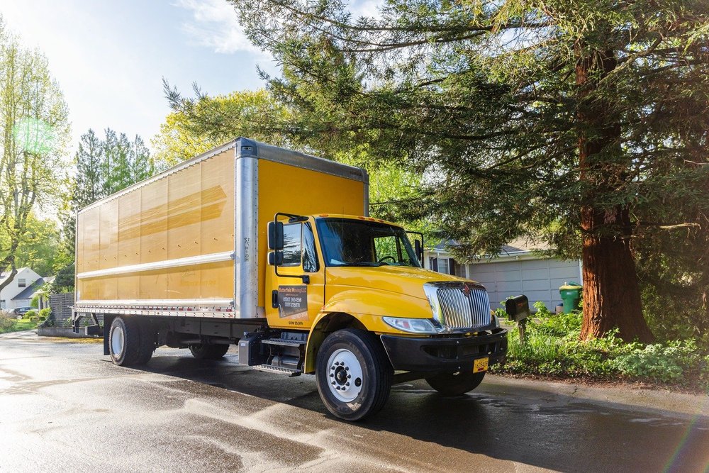 Butterfield yellow box truck parked on a tree-lined residential street, move in Keizer