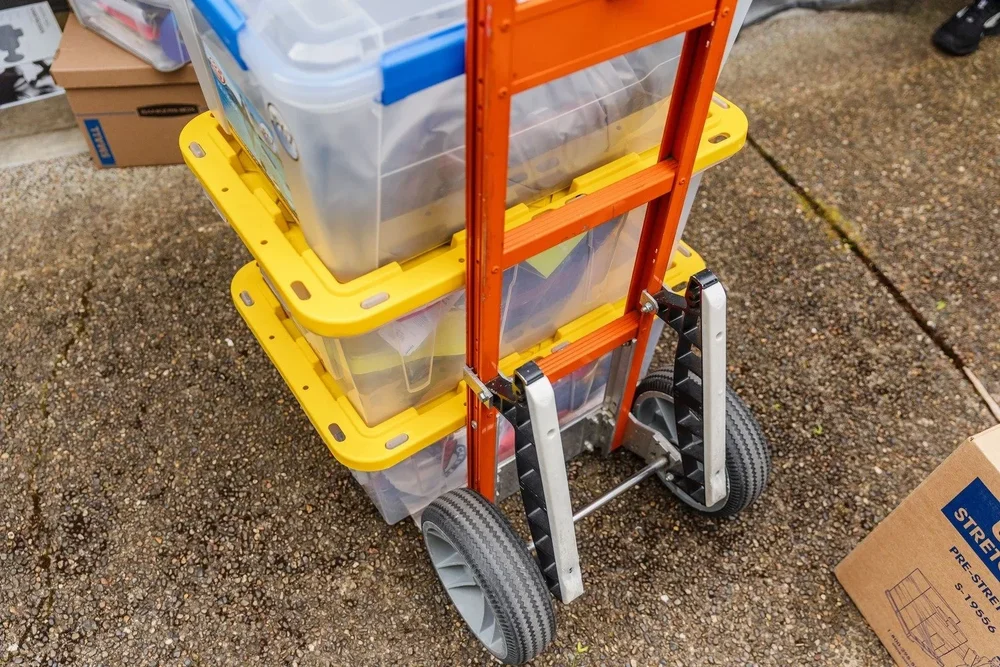 Hand truck stacked with plastic storage bins, move in Sandy