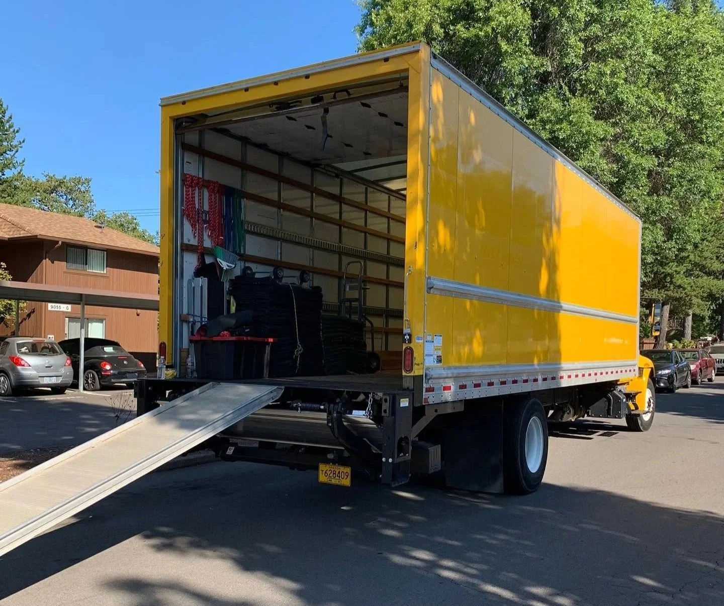 Yellow moving truck with ramp down outside an apartment complex, office relocation in Beaverton