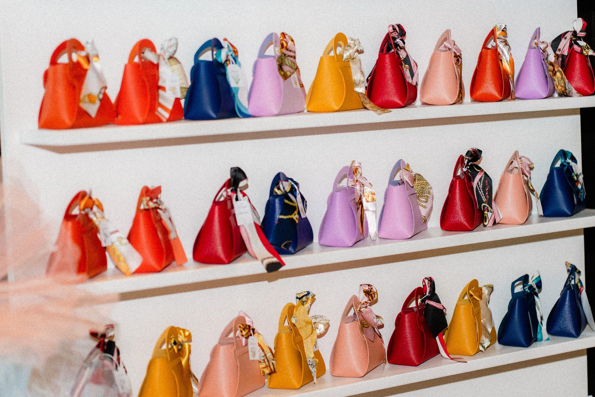 Colorful handbags displayed on white shelves.