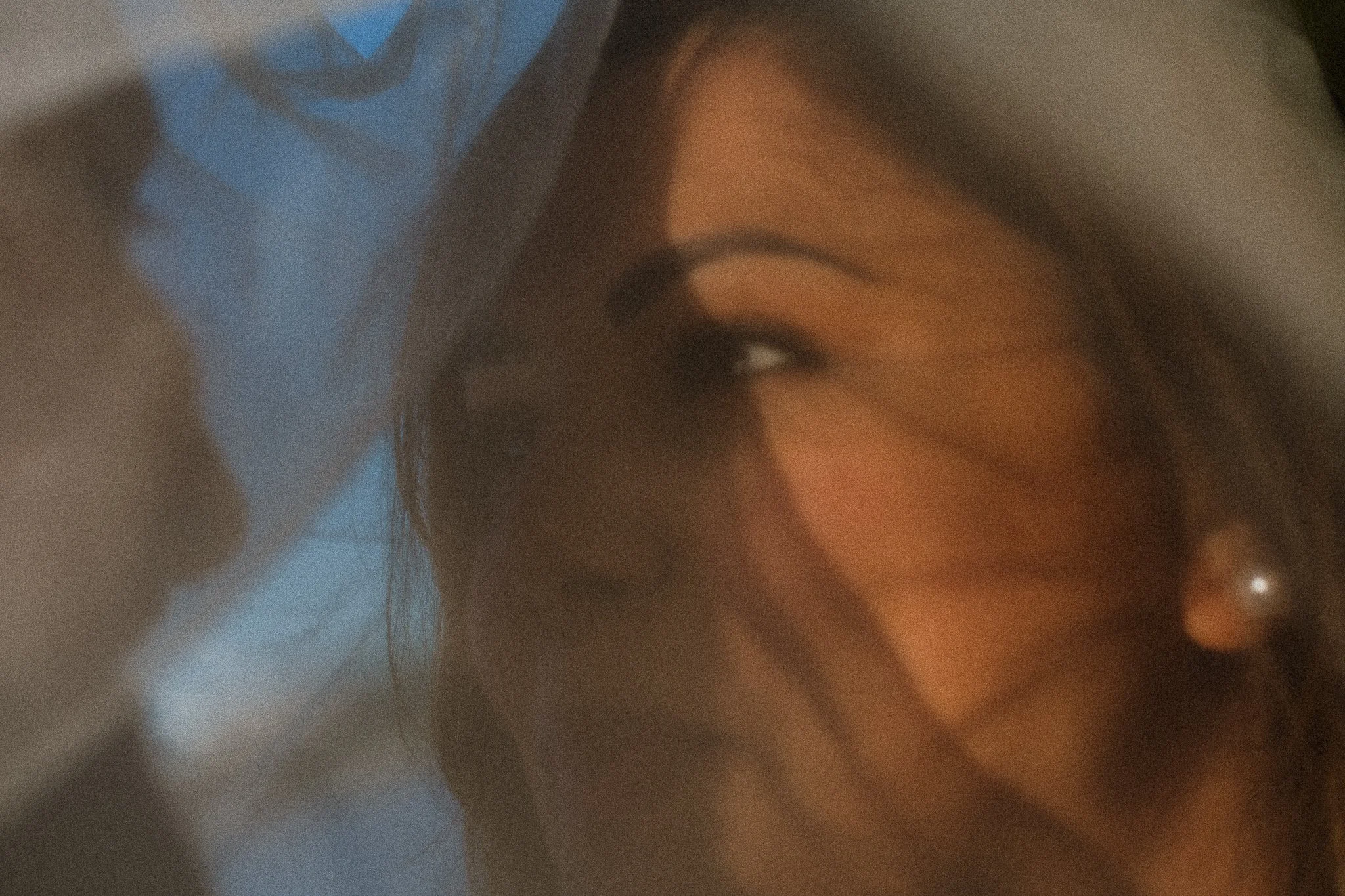 A close-up of a person's face showing their eye, eyebrow, and part of their nose. The person has dark hair and the background is blurred.