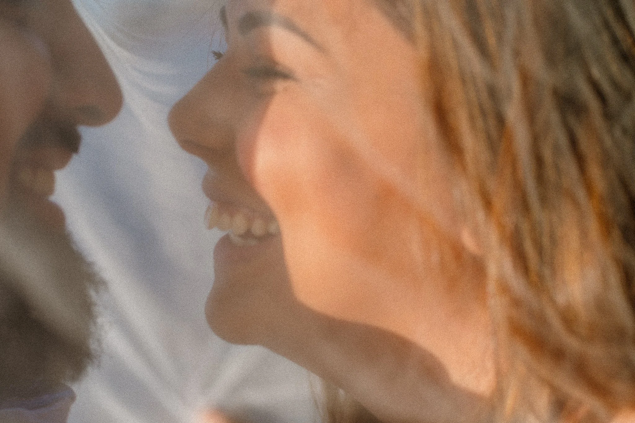Close-up of a person's face with lips slightly parted, with curly hair and clear skin.