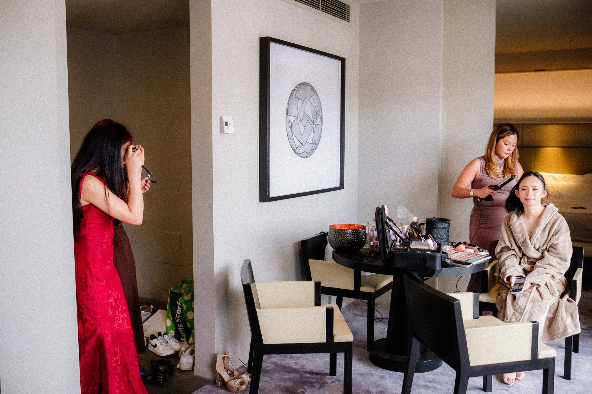 Two women in a makeup studio with makeup tools, one sitting and the other standing, while makeup brushes, palettes, and other accessories are placed on the table.