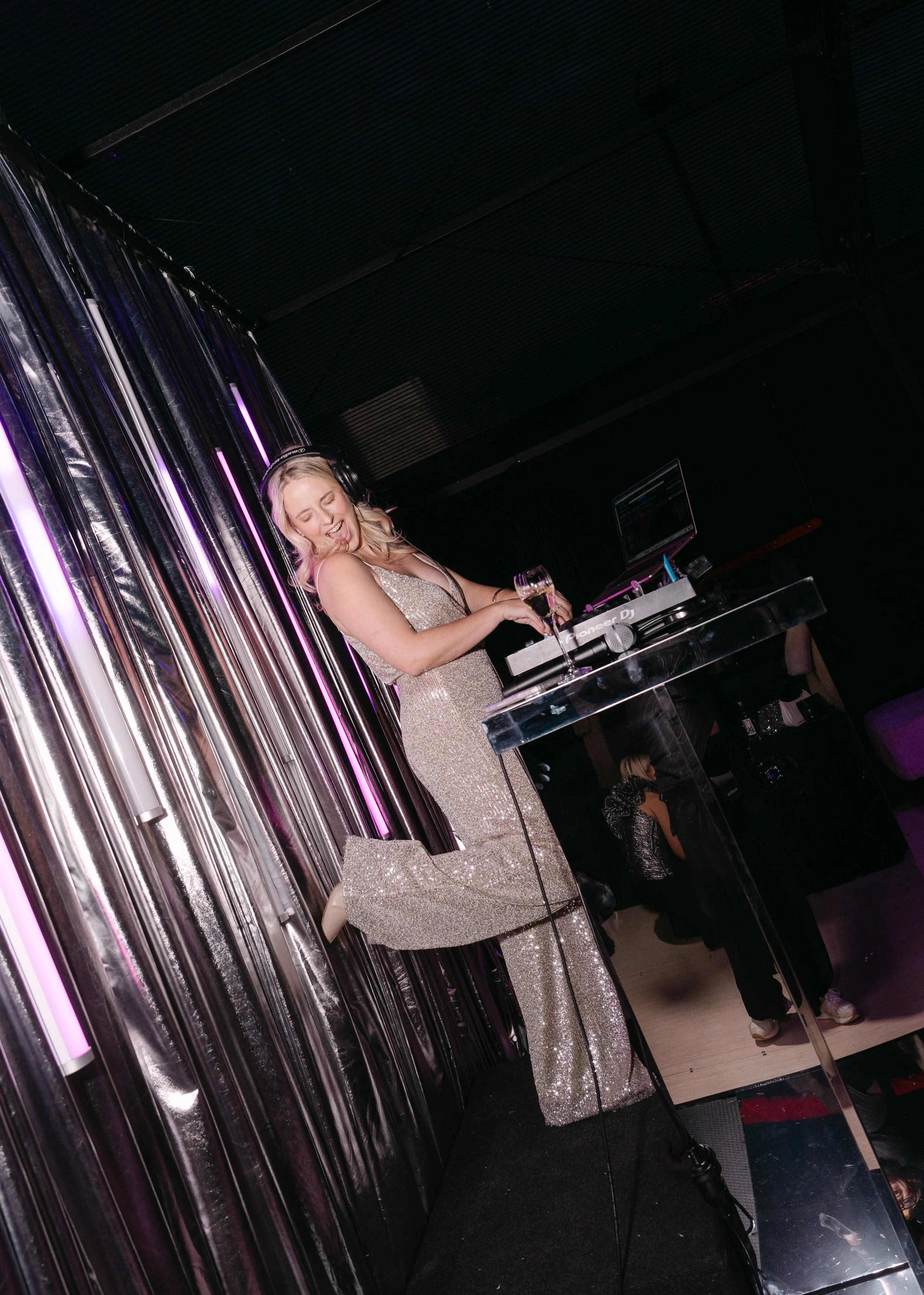 A woman in a sparkling dress DJing a Studio 54 themed 50th.