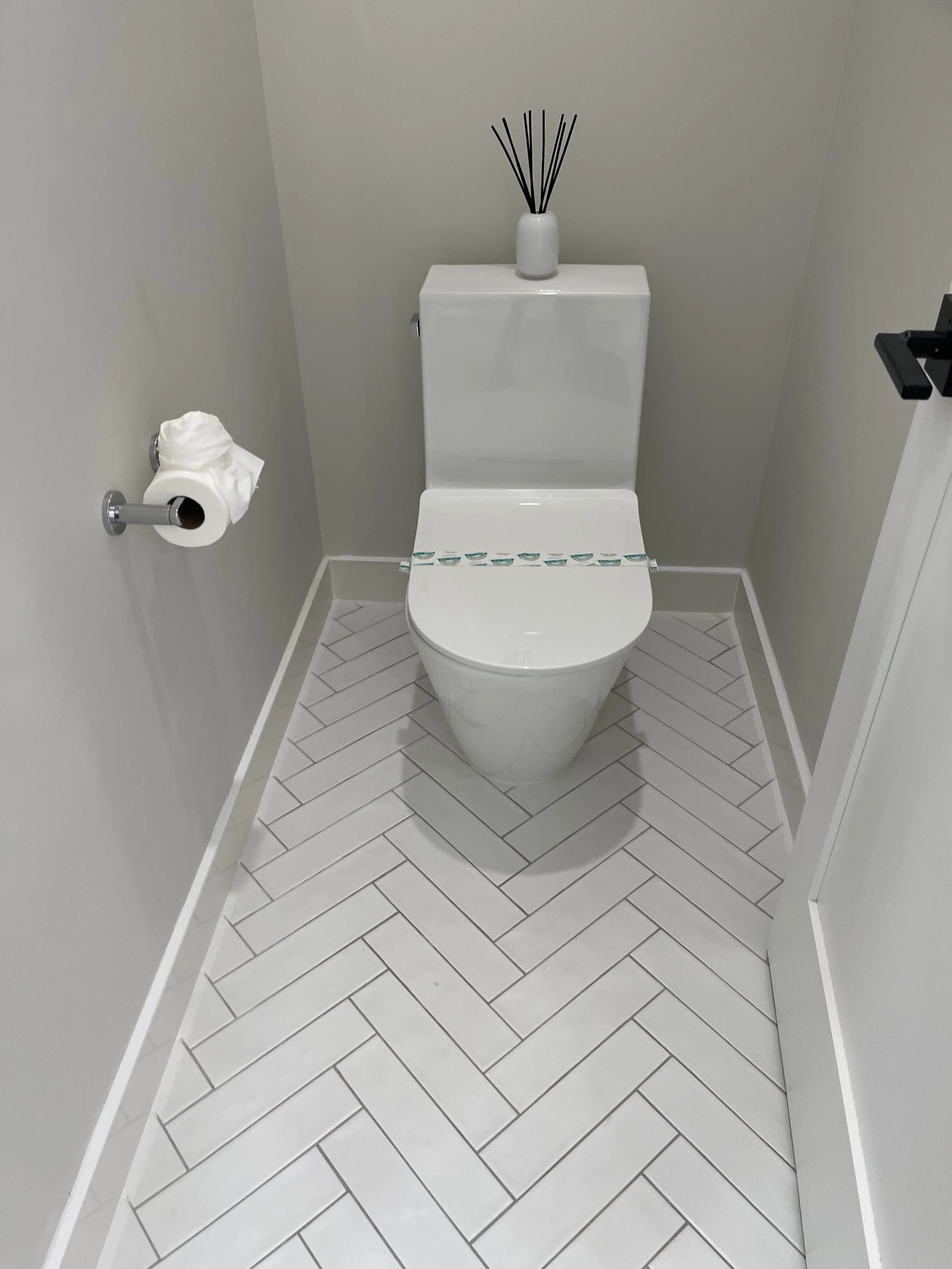 Clean half-bath with polished fixtures and herringbone tile floor