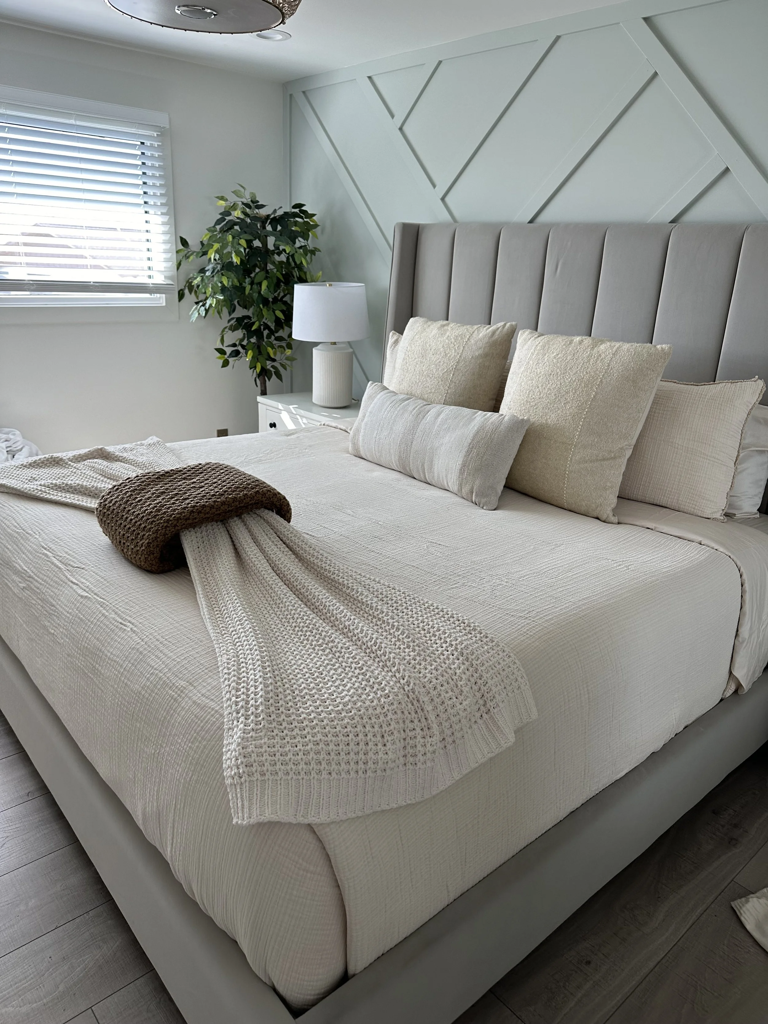 Freshly made bed with layered neutral bedding and a tidy nightstand.