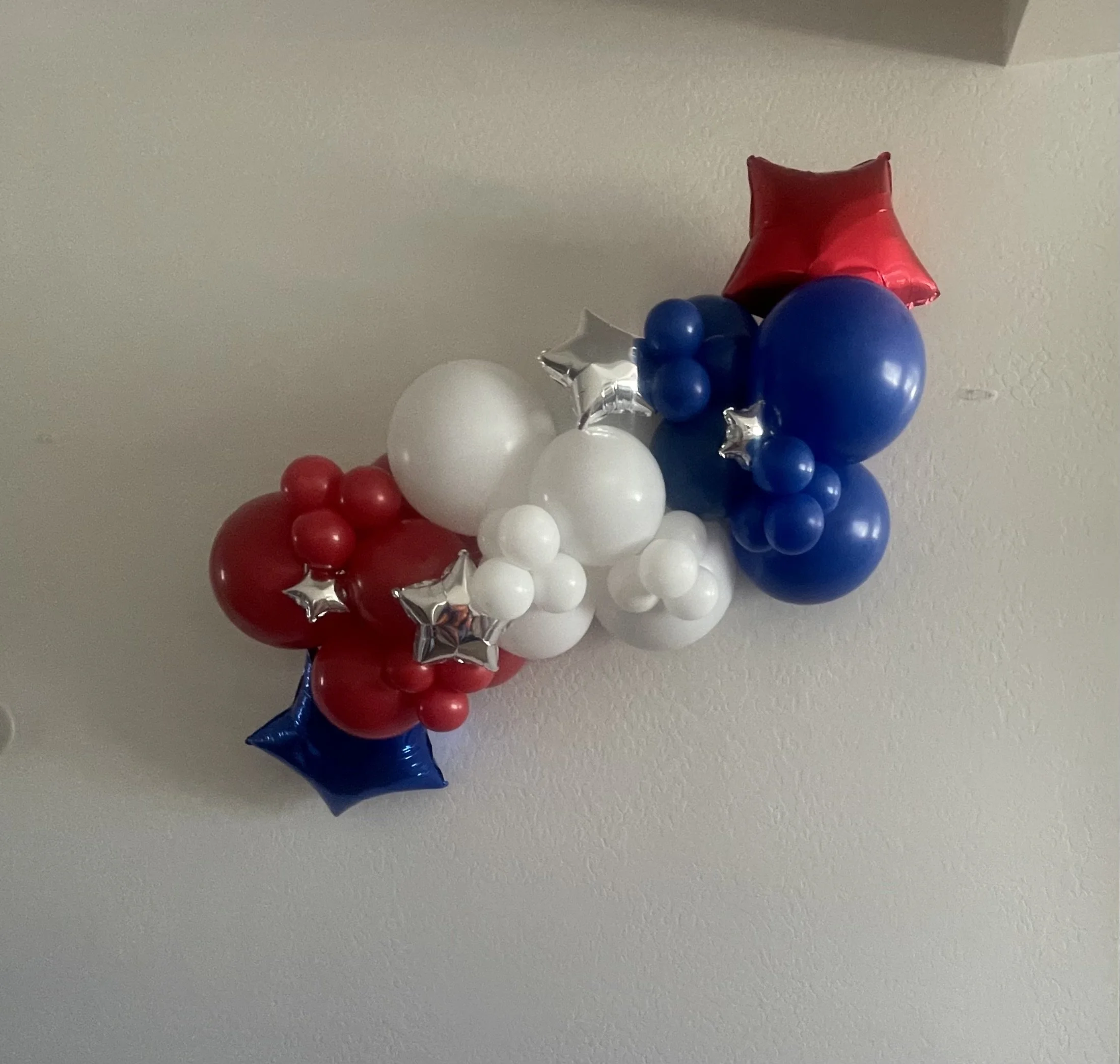 Balloon arrangement with red, white, blue, and silver star-shaped balloons, with a large red balloon at the top.