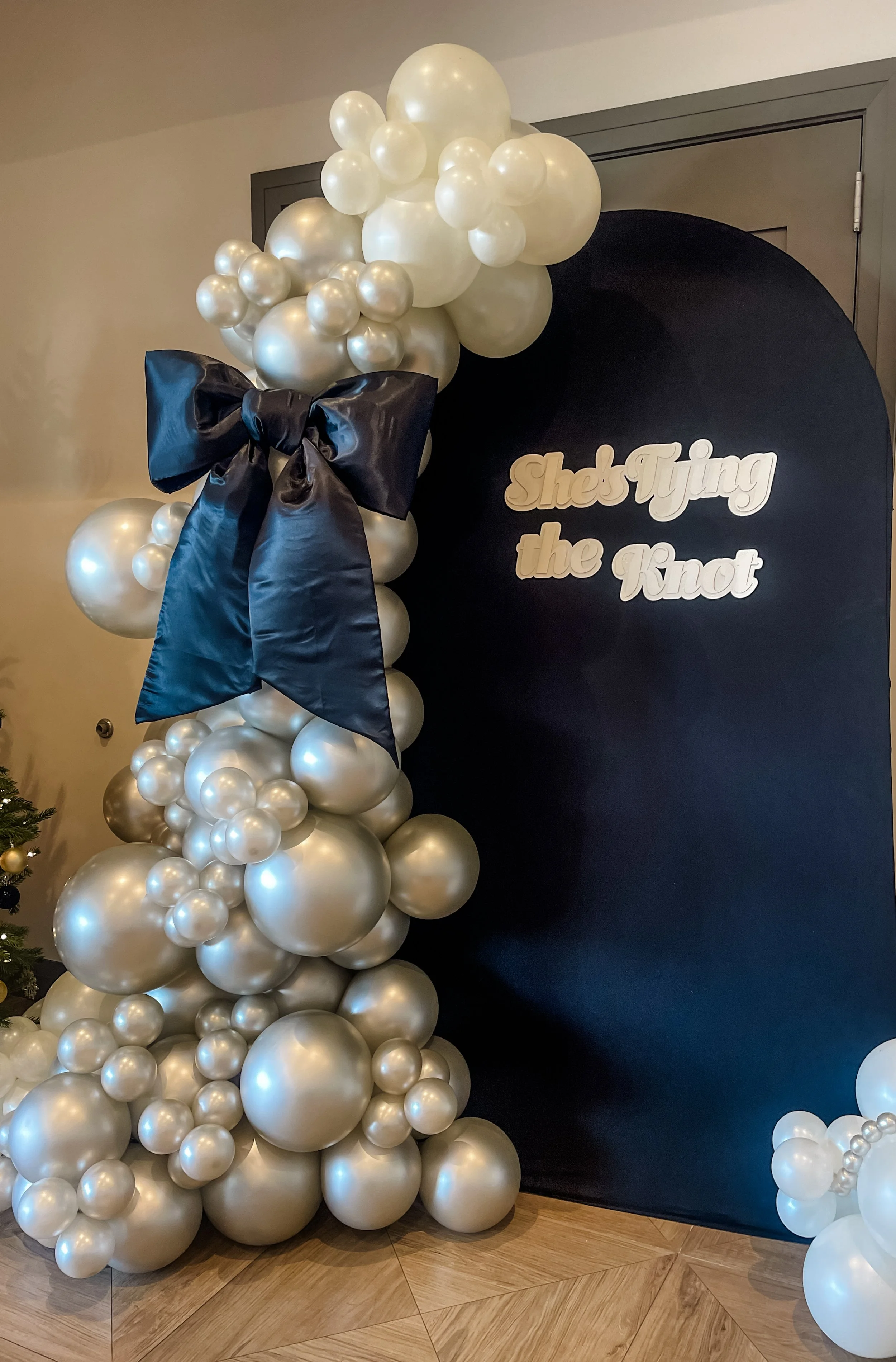  'She’s Tying the Knot' Bridal Shower Balloons- Organic pearl garland on black backdrop with oversized black satin bow