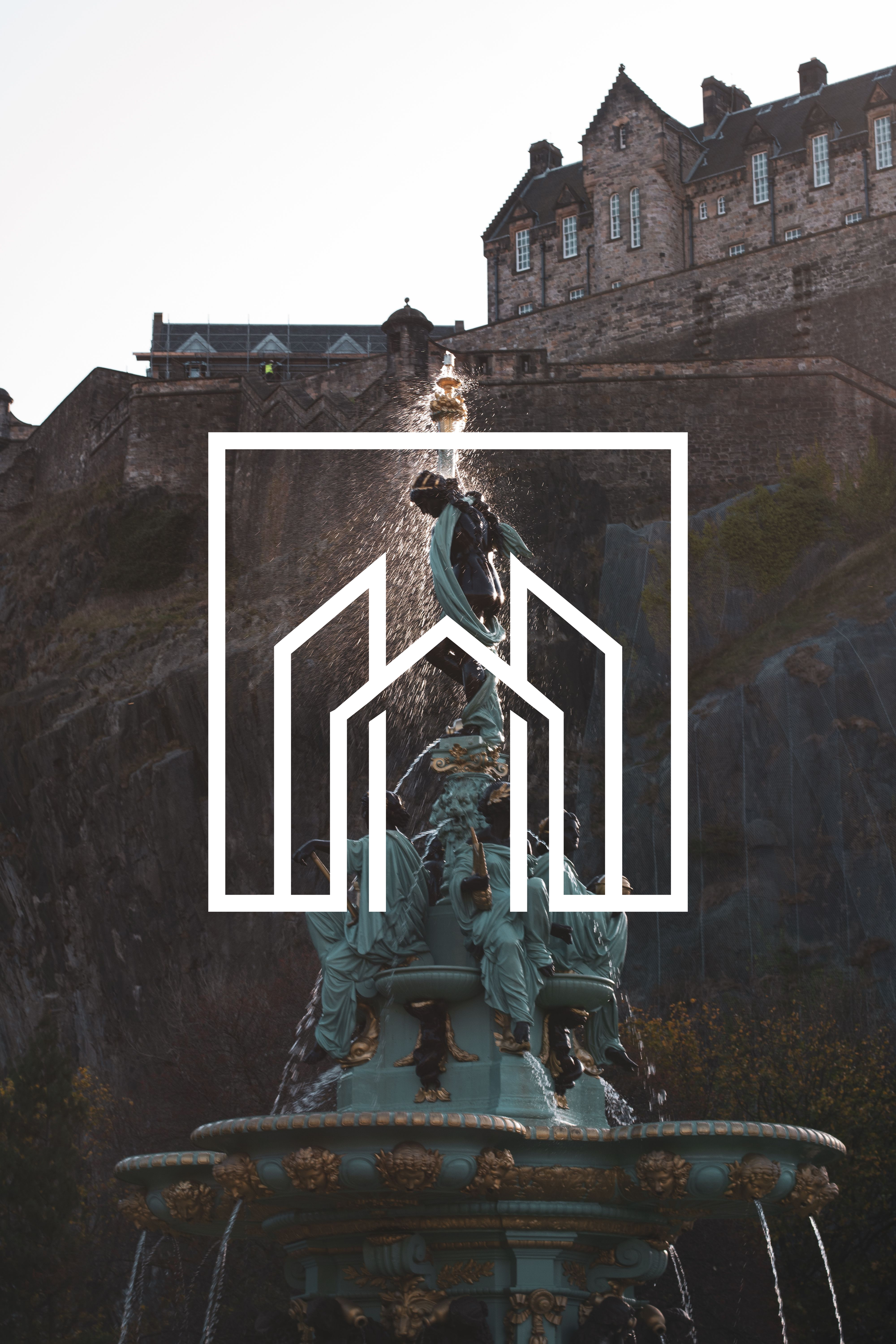 The image shows a historic ornate fountain with multiple statues and water cascading down, situated outdoors with a large stone castle on a hill in the background.