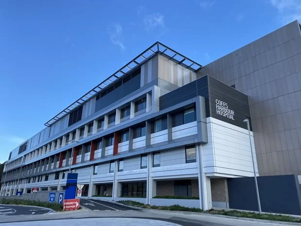 Front view of Coffs Harbour Hospital showing modern multi-story building with parking lot.
