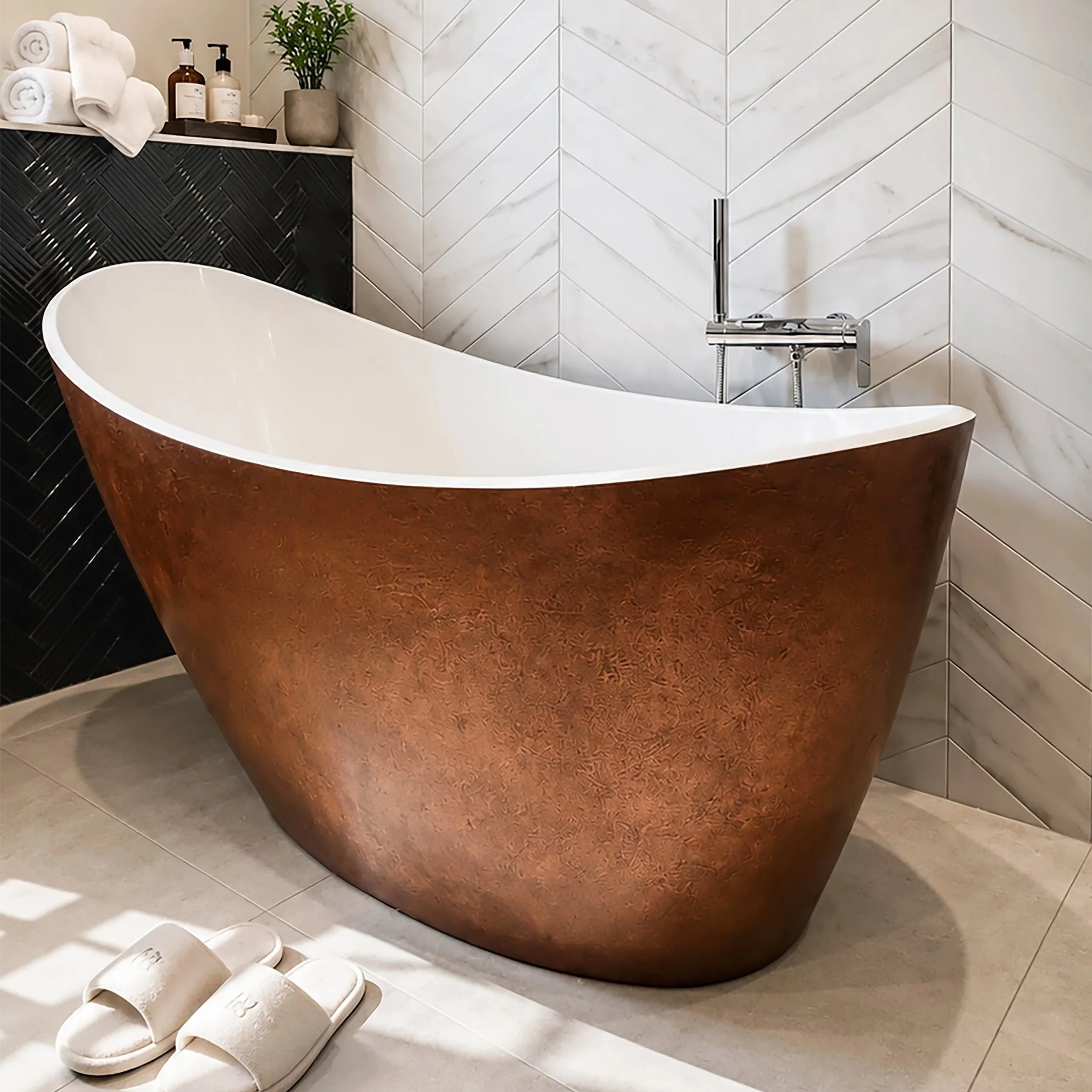 A bathroom with a white, free-standing bathtub with a reddish-brown exterior, white slippers on the floor, a black woven tile wall behind the bathtub, a white tiled wall with marble veining, a grey pot with a green plant, and arranged towels with soap and lotion bottles.