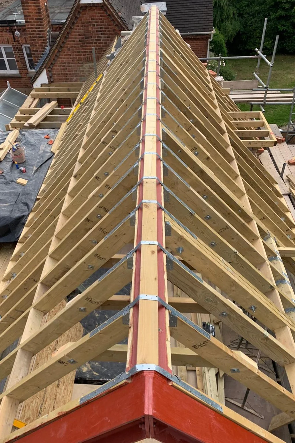 Structural framework of a building roof under construction with wooden trusses and scaffolding.